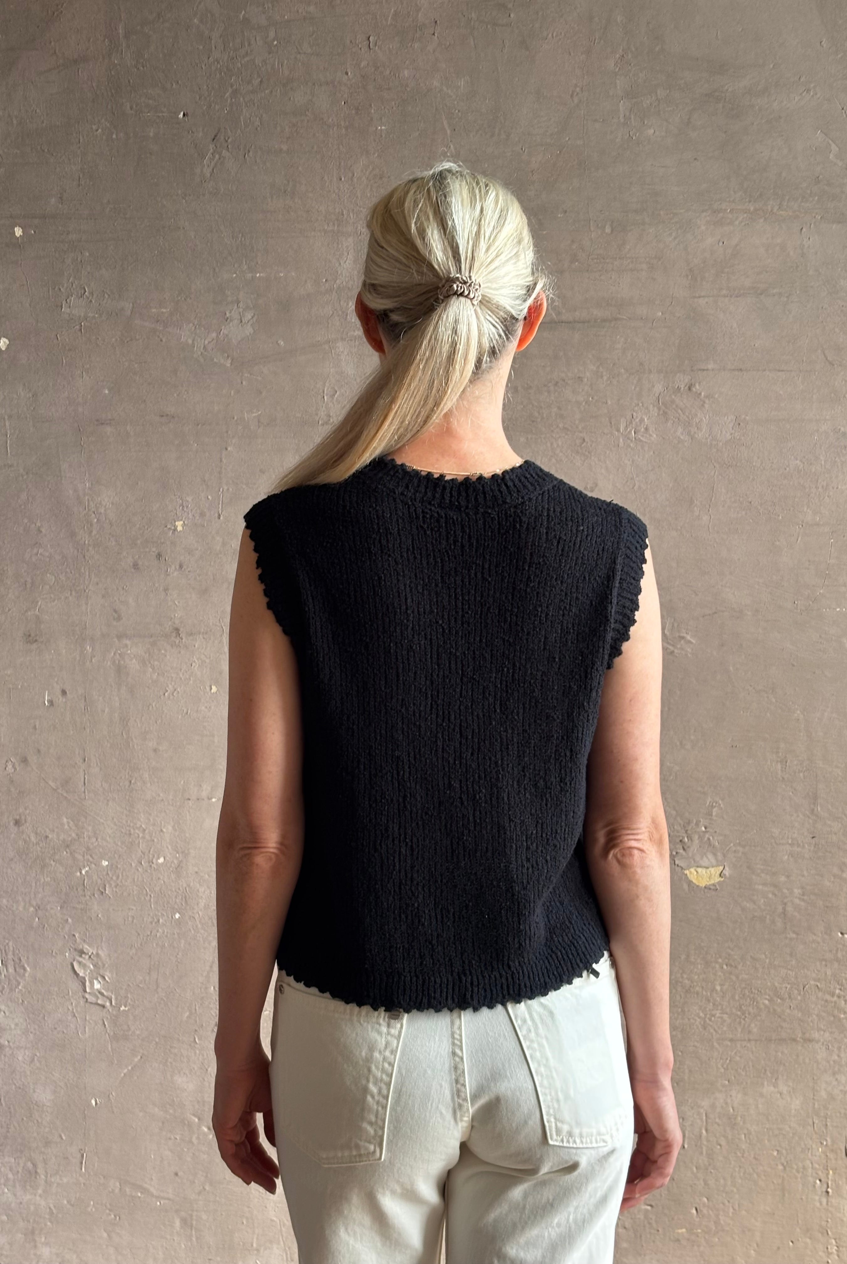 Mature woman wearing Rachel Comey designer Relent sleeveless black cotton knit top with a scalloped edges