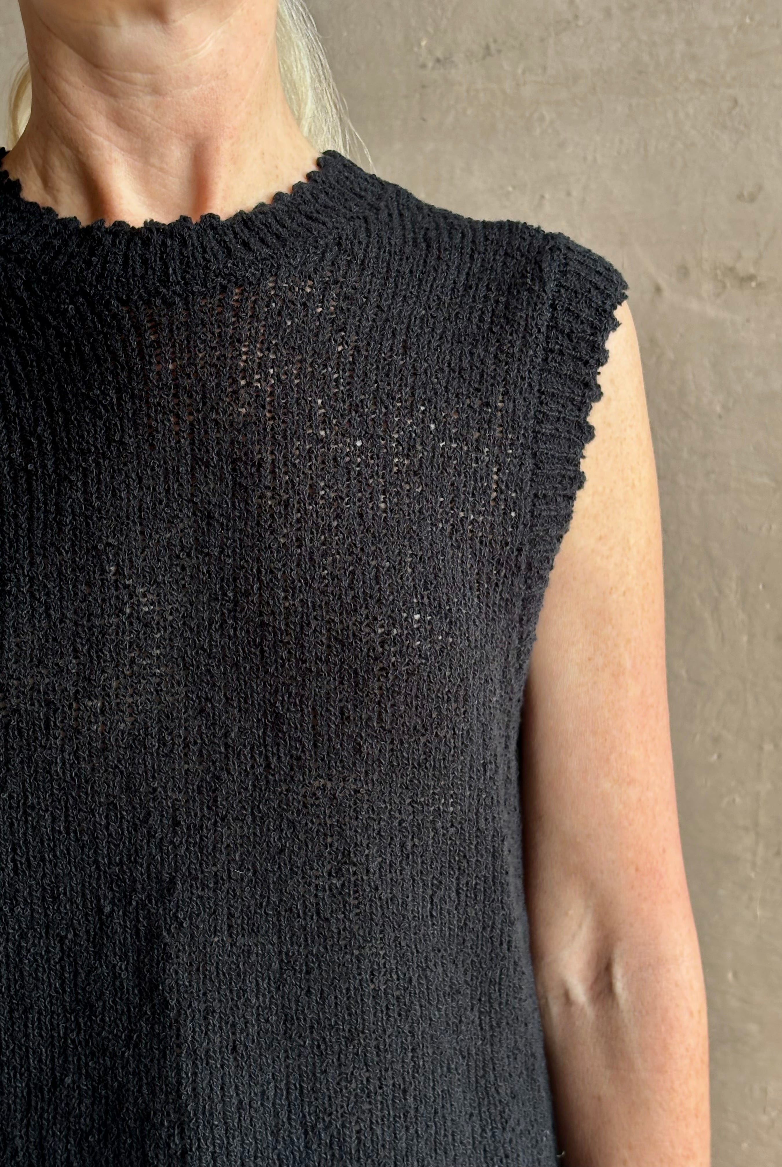 Mature woman wearing Rachel Comey designer Relent sleeveless black cotton knit top with a scalloped edges