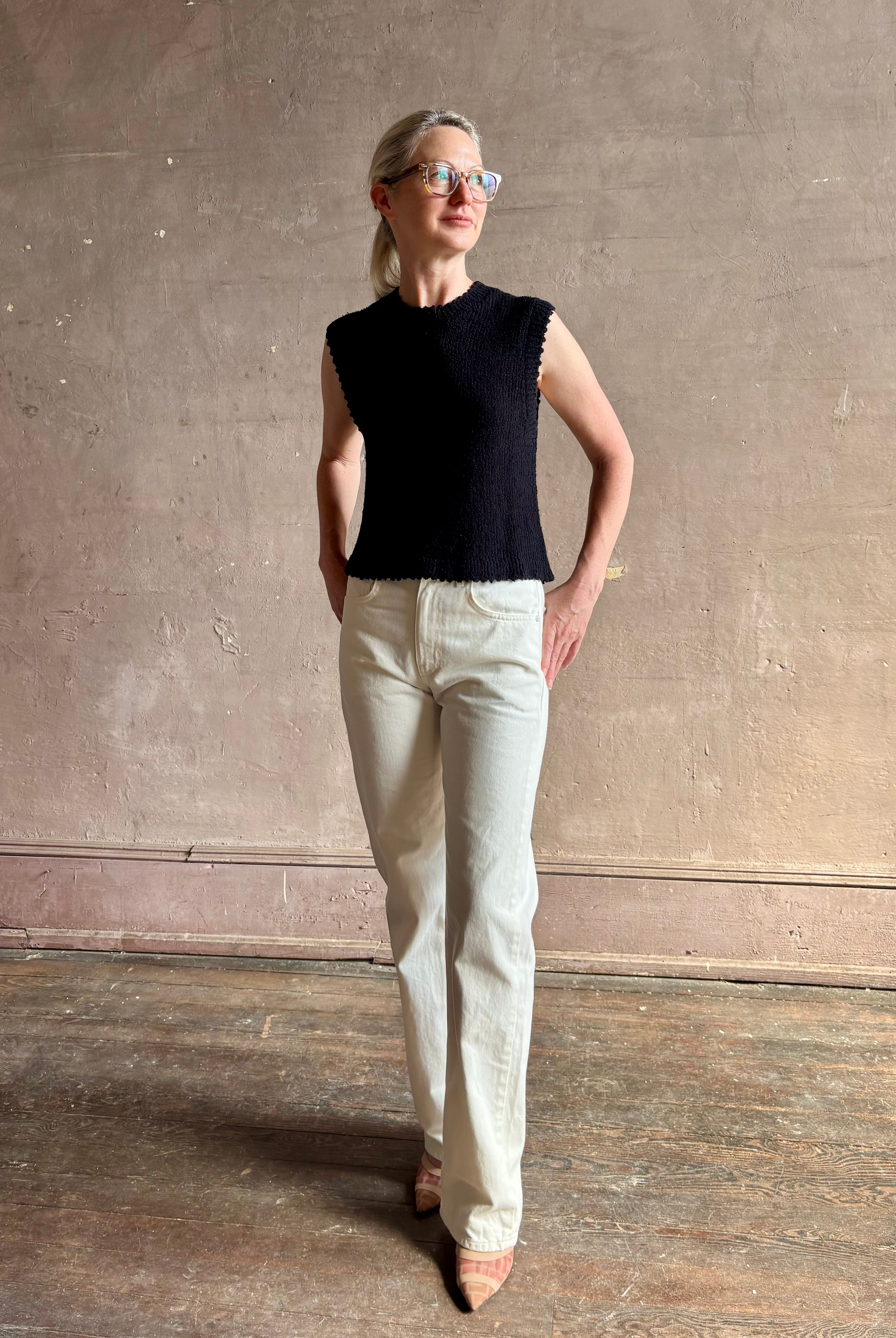 Mature woman wearing Rachel Comey designer Relent sleeveless black cotton knit top with a scalloped edges