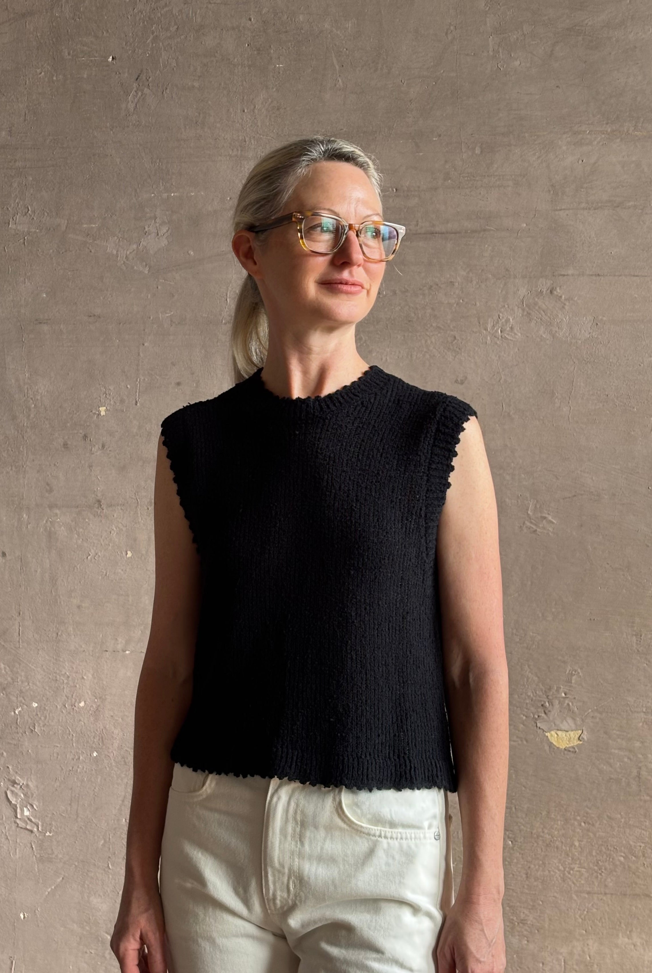 Mature woman wearing Rachel Comey designer Relent sleeveless black cotton knit top with a scalloped edges