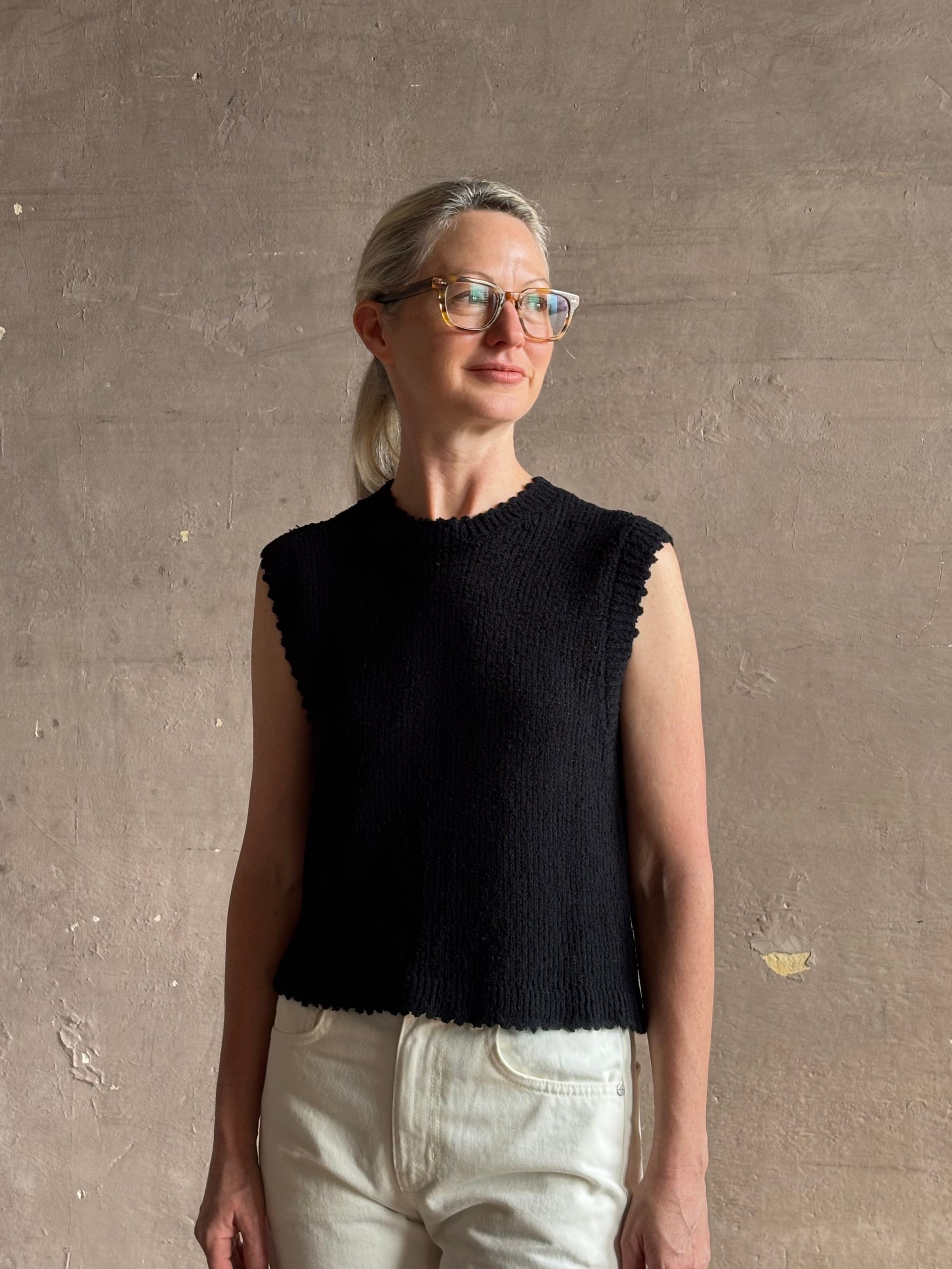 Mature woman wearing Rachel Comey designer Relent sleeveless black cotton knit top with a scalloped edges