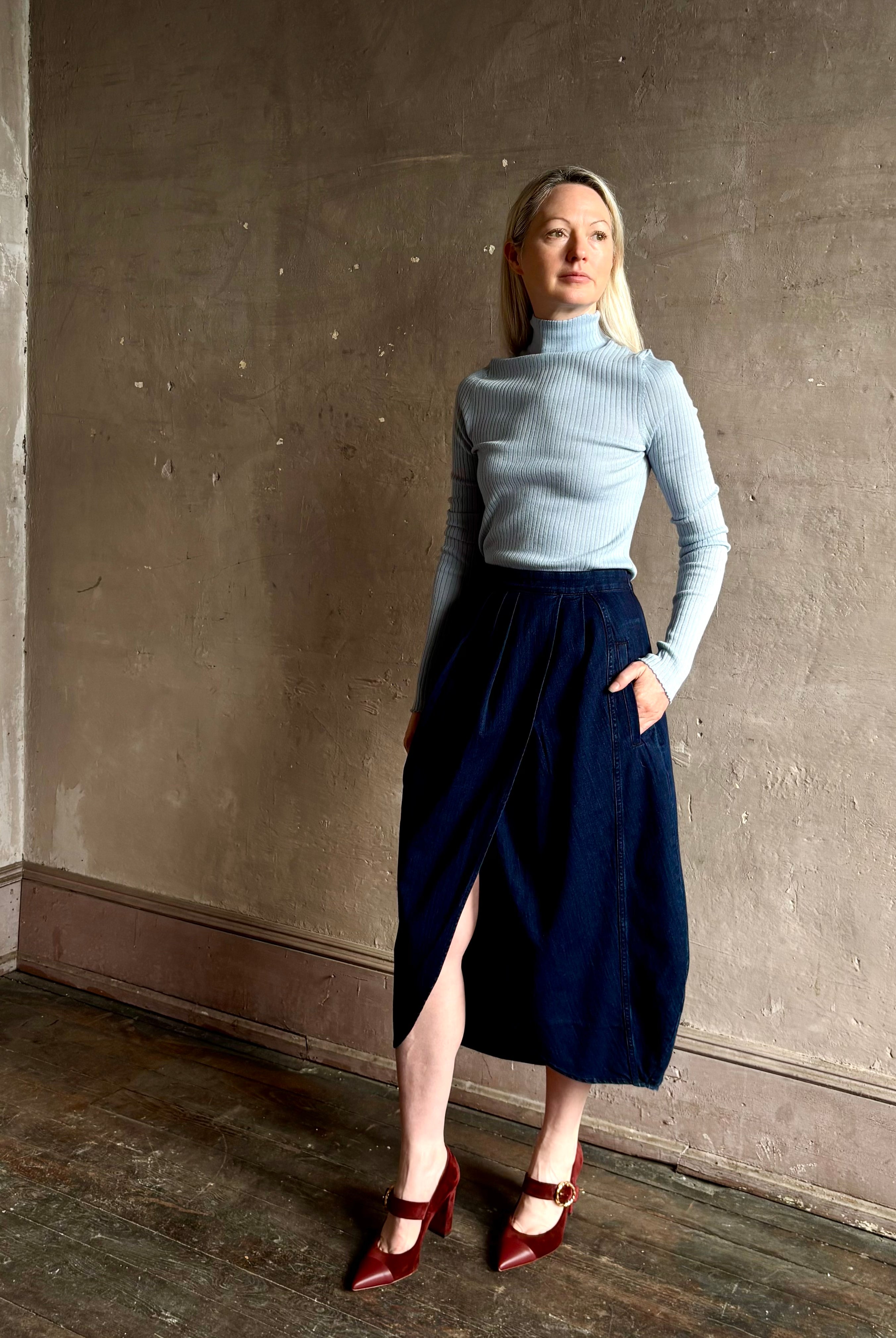 Woman wearing Rachel Comey dark wash denim midi Sobre skirt wrap-style front slit tulip design and side pockets