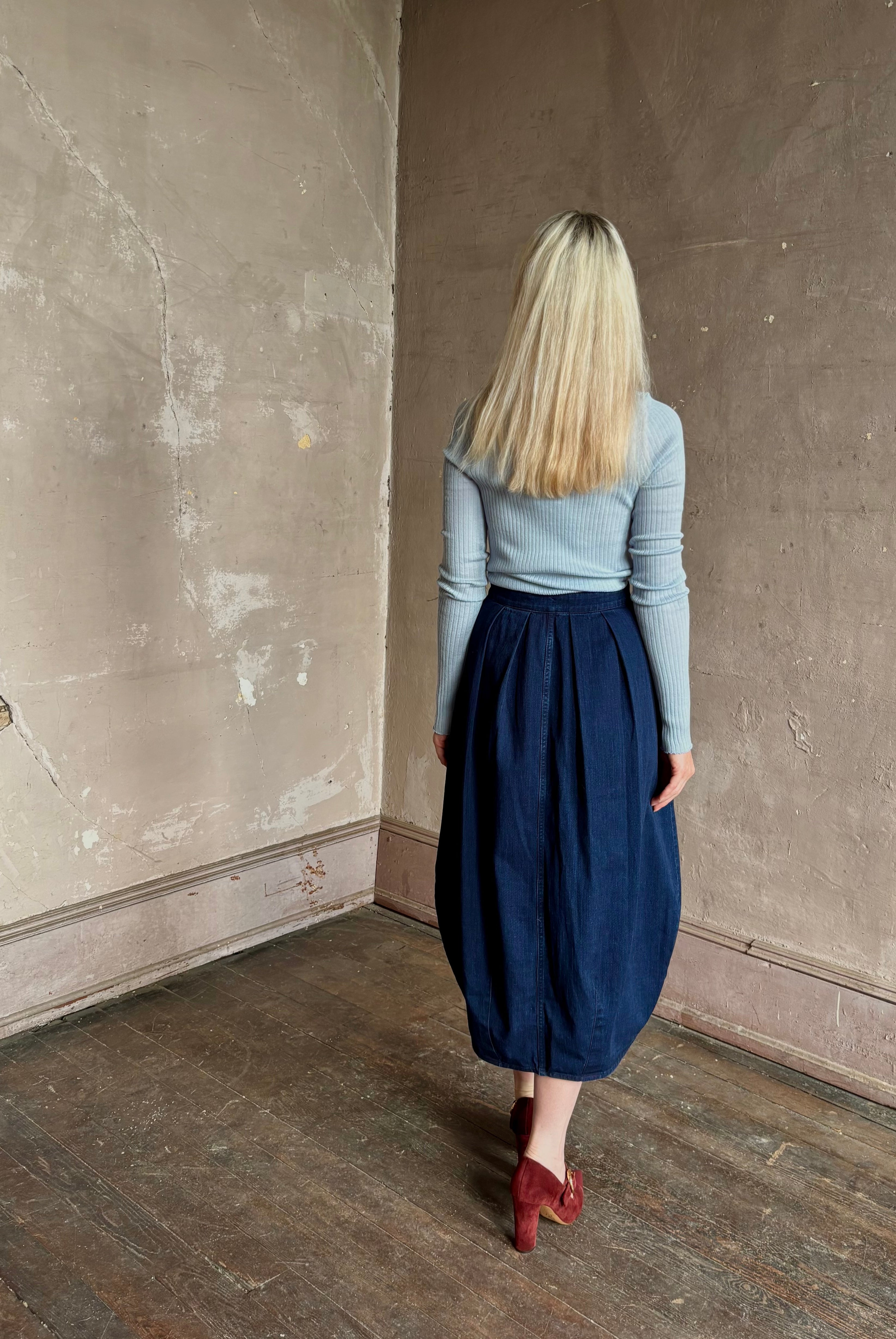 Woman wearing Rachel Comey dark wash denim midi Sobre skirt wrap-style front slit tulip design and side pockets