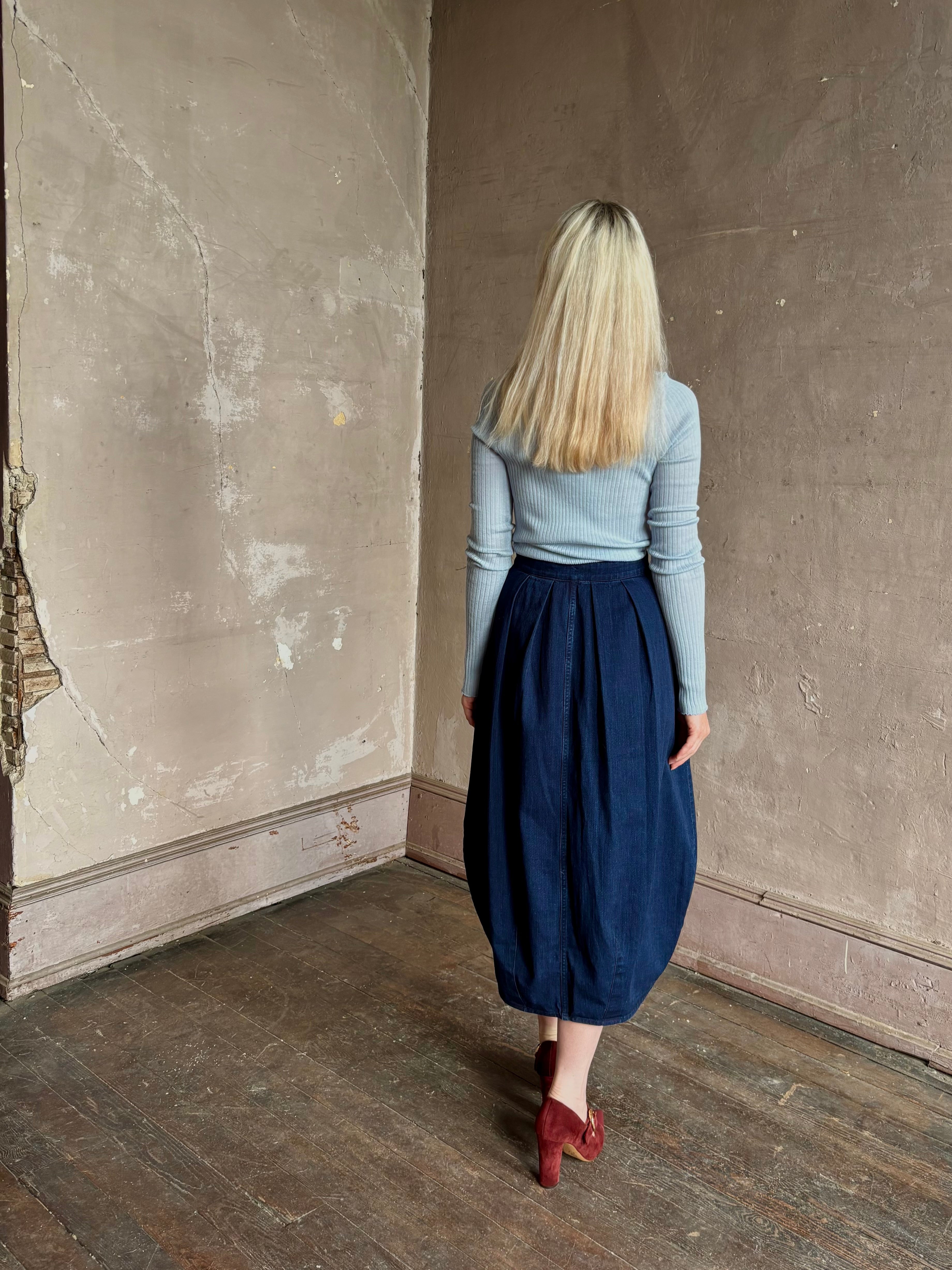 Woman wearing Rachel Comey dark wash denim midi Sobre skirt wrap-style front slit tulip design and side pockets