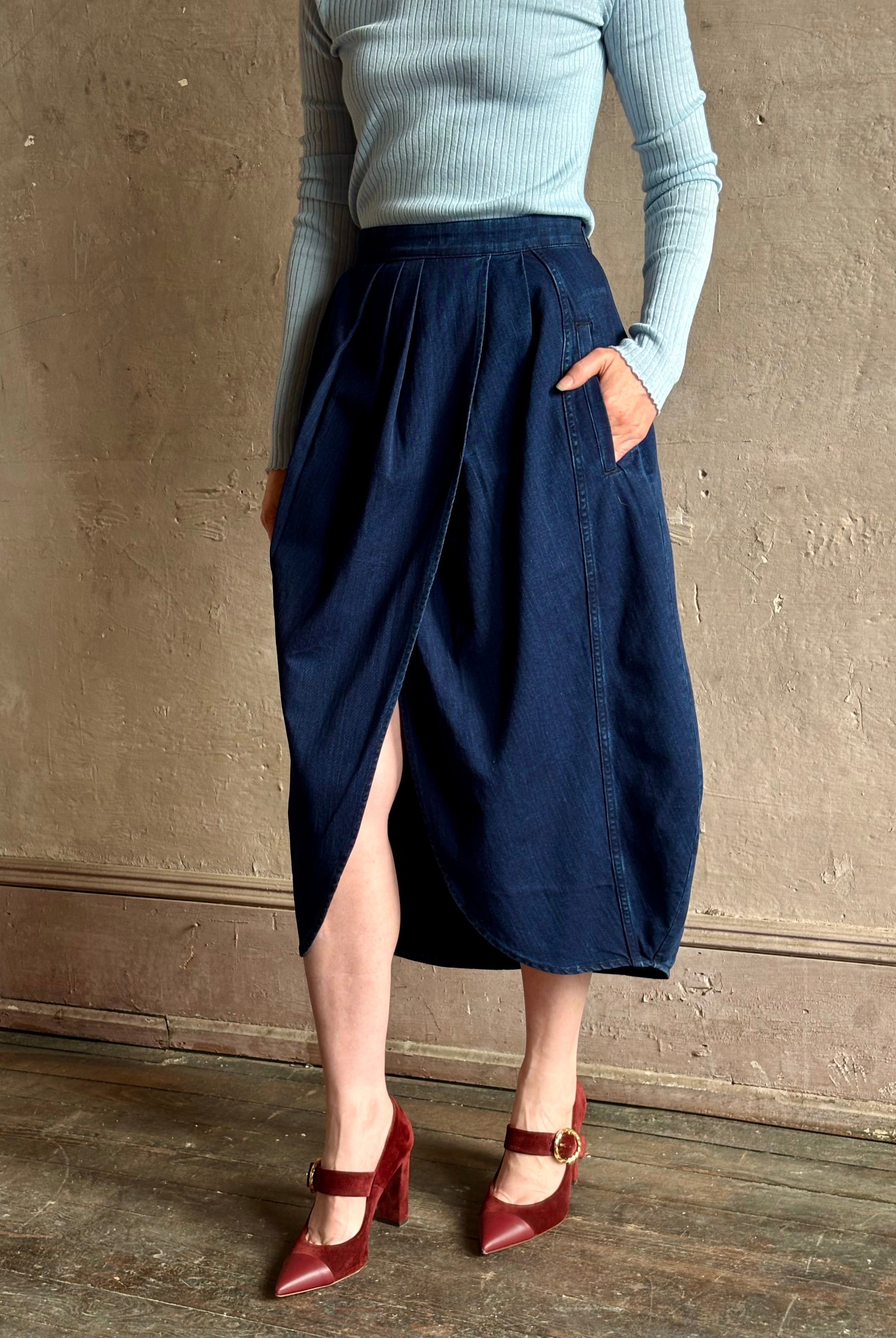 Woman wearing Rachel Comey dark wash denim midi Sobre skirt wrap-style front slit tulip design and side pockets