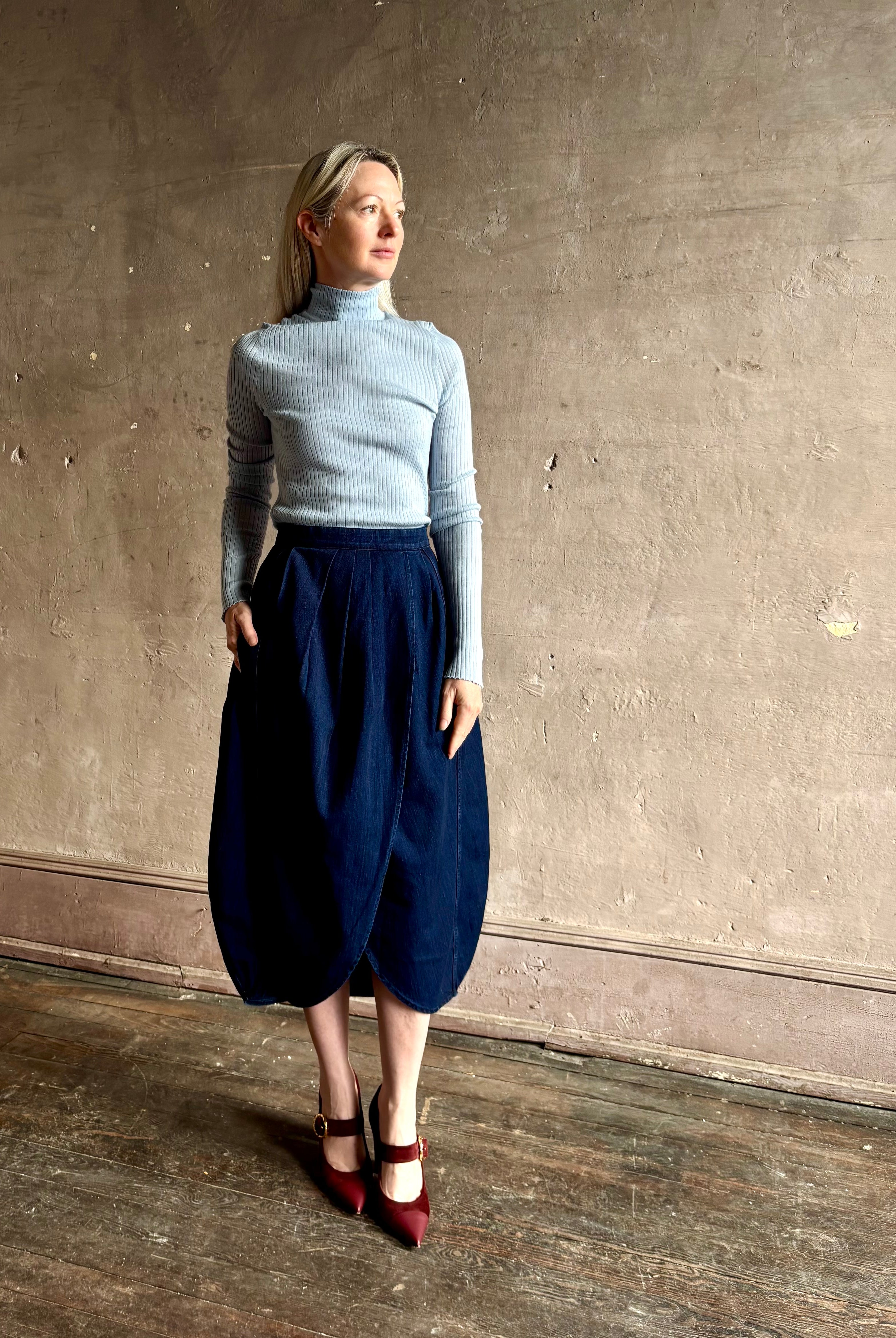 Woman wearing Rachel Comey dark wash denim midi Sobre skirt wrap-style front slit tulip design and side pockets