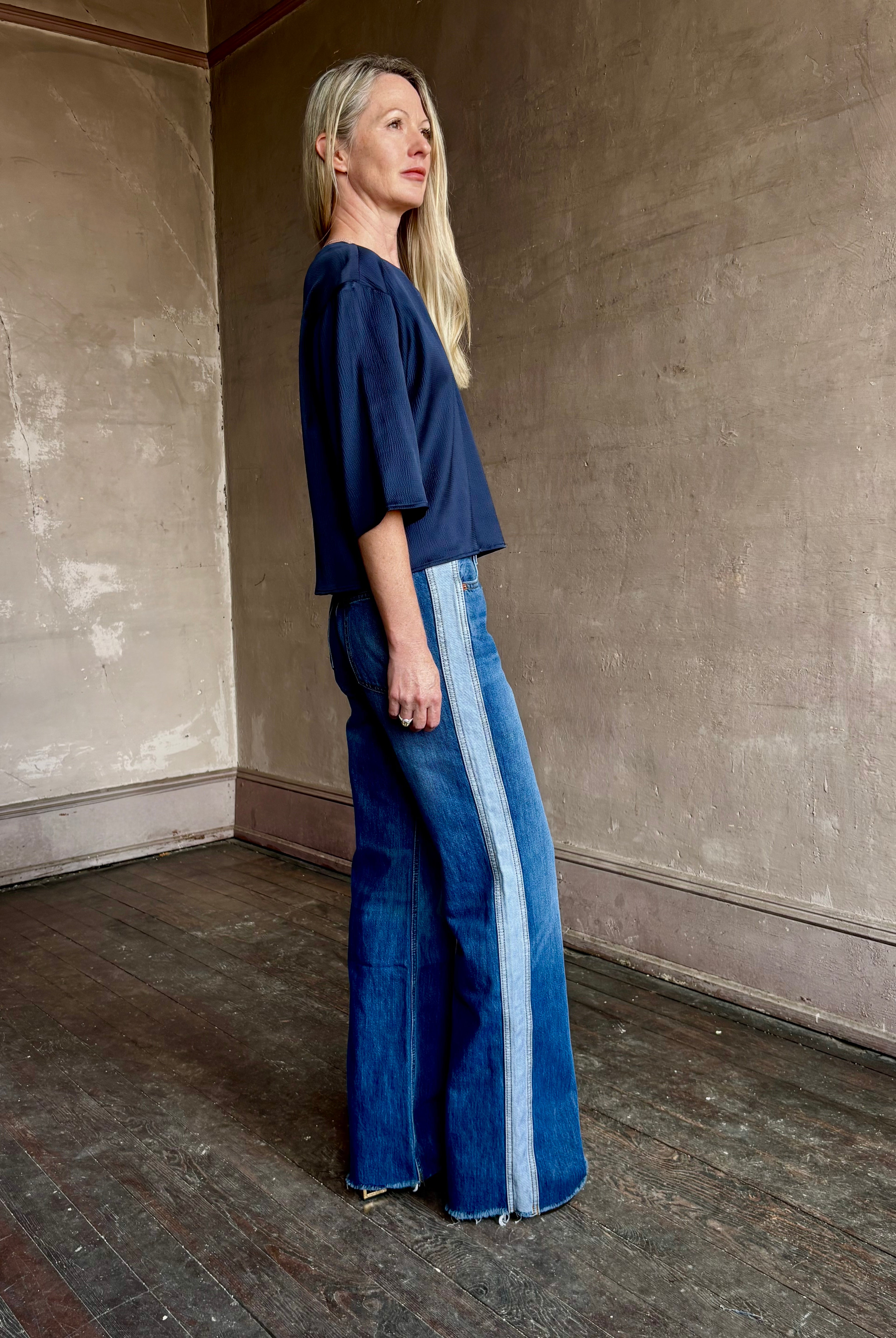 Image of mature woman wearing mid-rise jean ReDone track Californian denim with light blue stripe down side in Viper blue wash