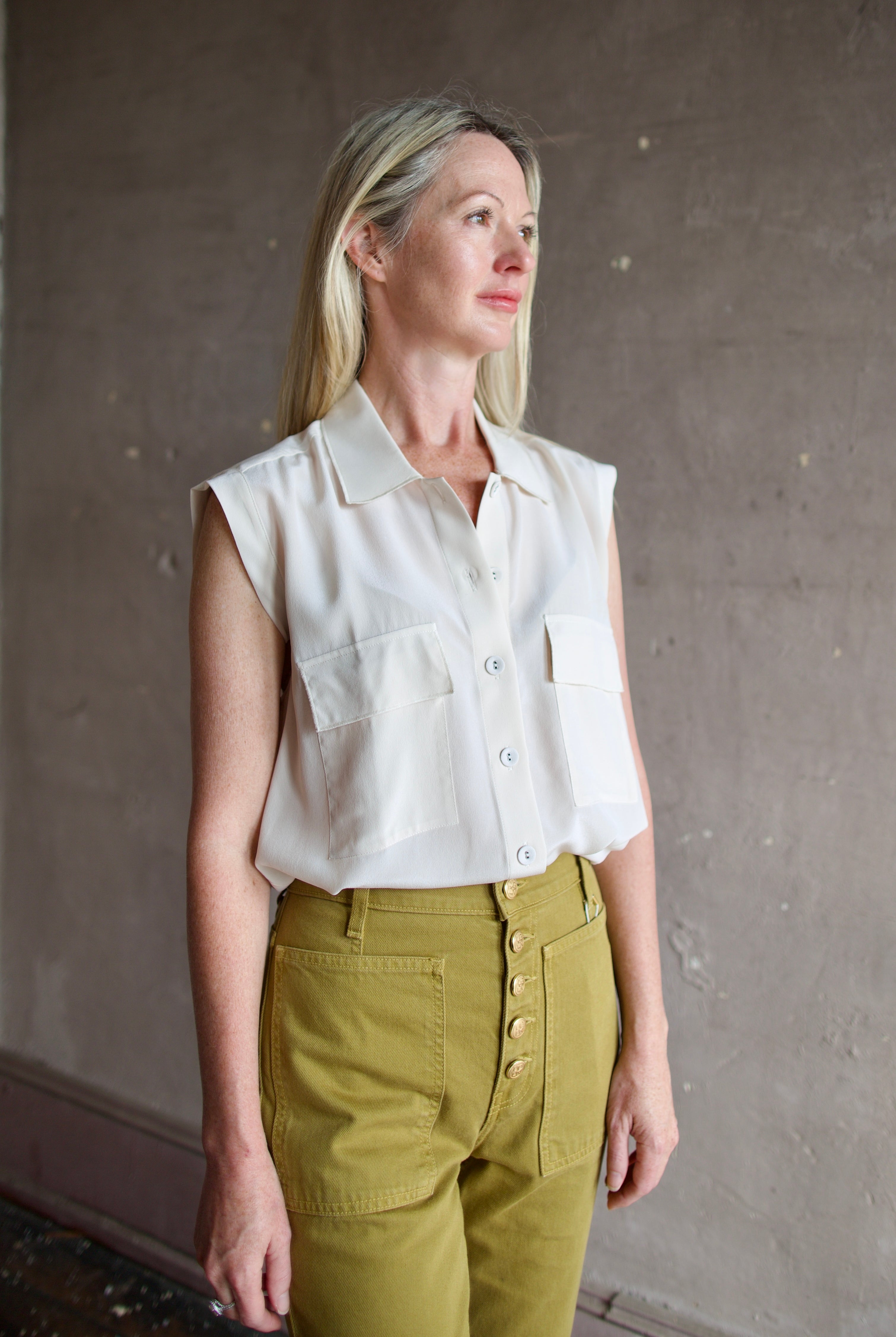 Model wearing a beige silk button down blouse by Rachel Comey in a modern silhouette