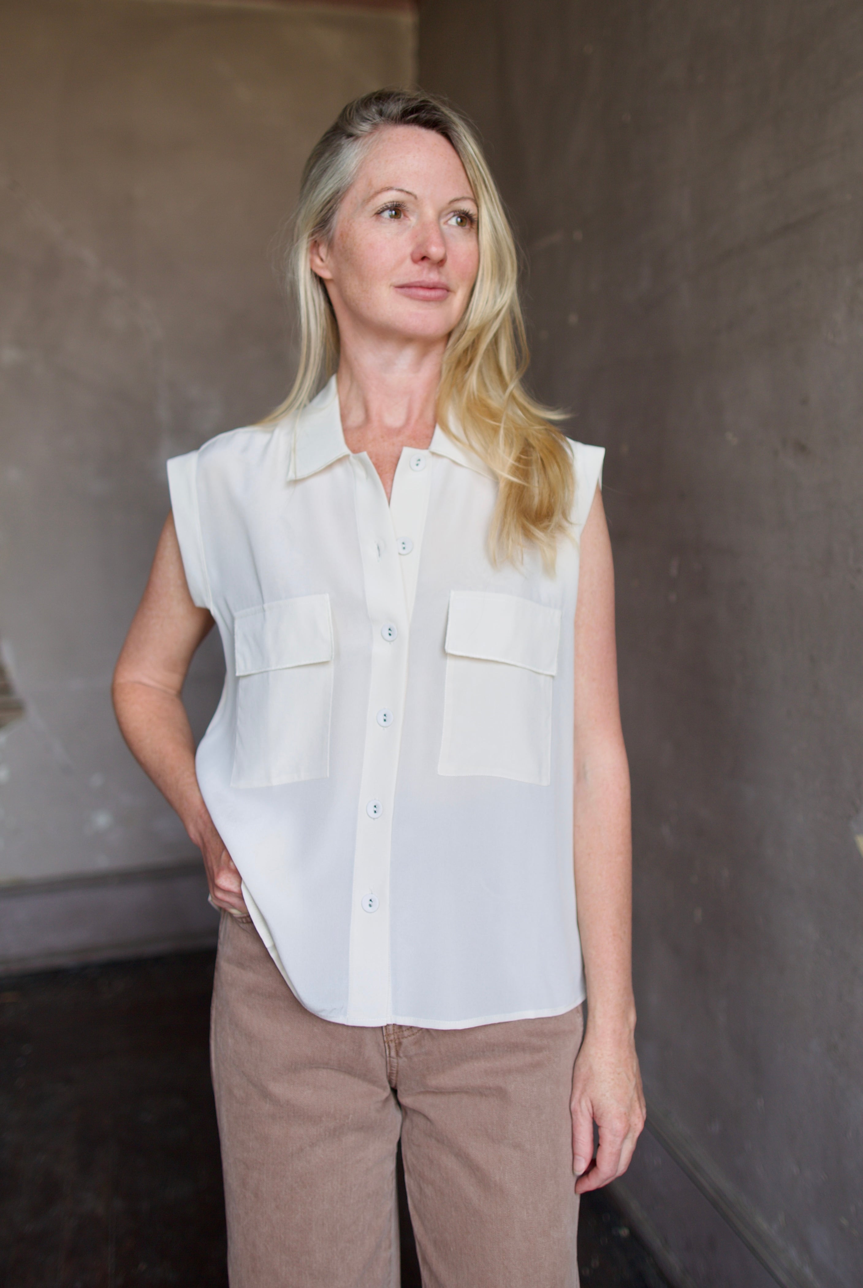 Model wearing a beige silk button down blouse by Rachel Comey in a modern silhouette