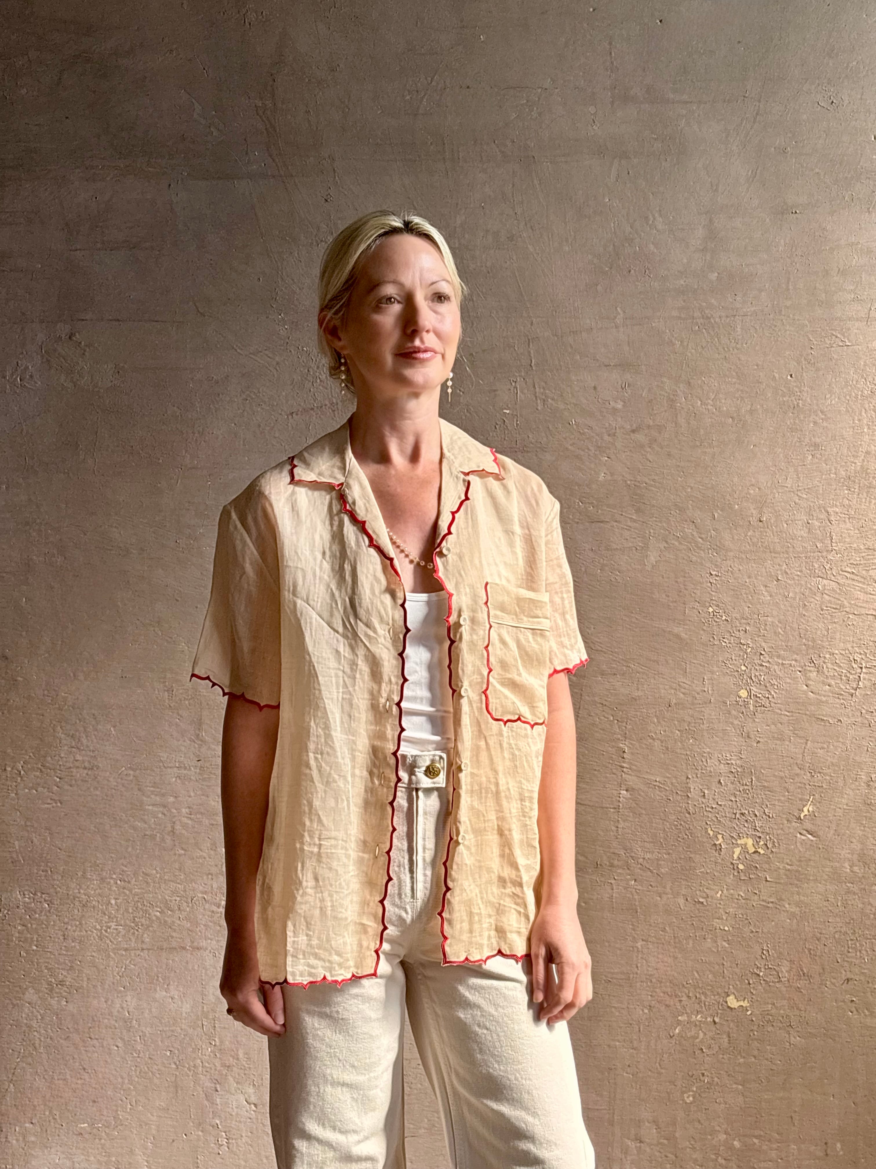 Mature woman wearing a beige retro inspired blouse with scalloped red trim by New York based Women's clothing designer Rachel Comey in raimey