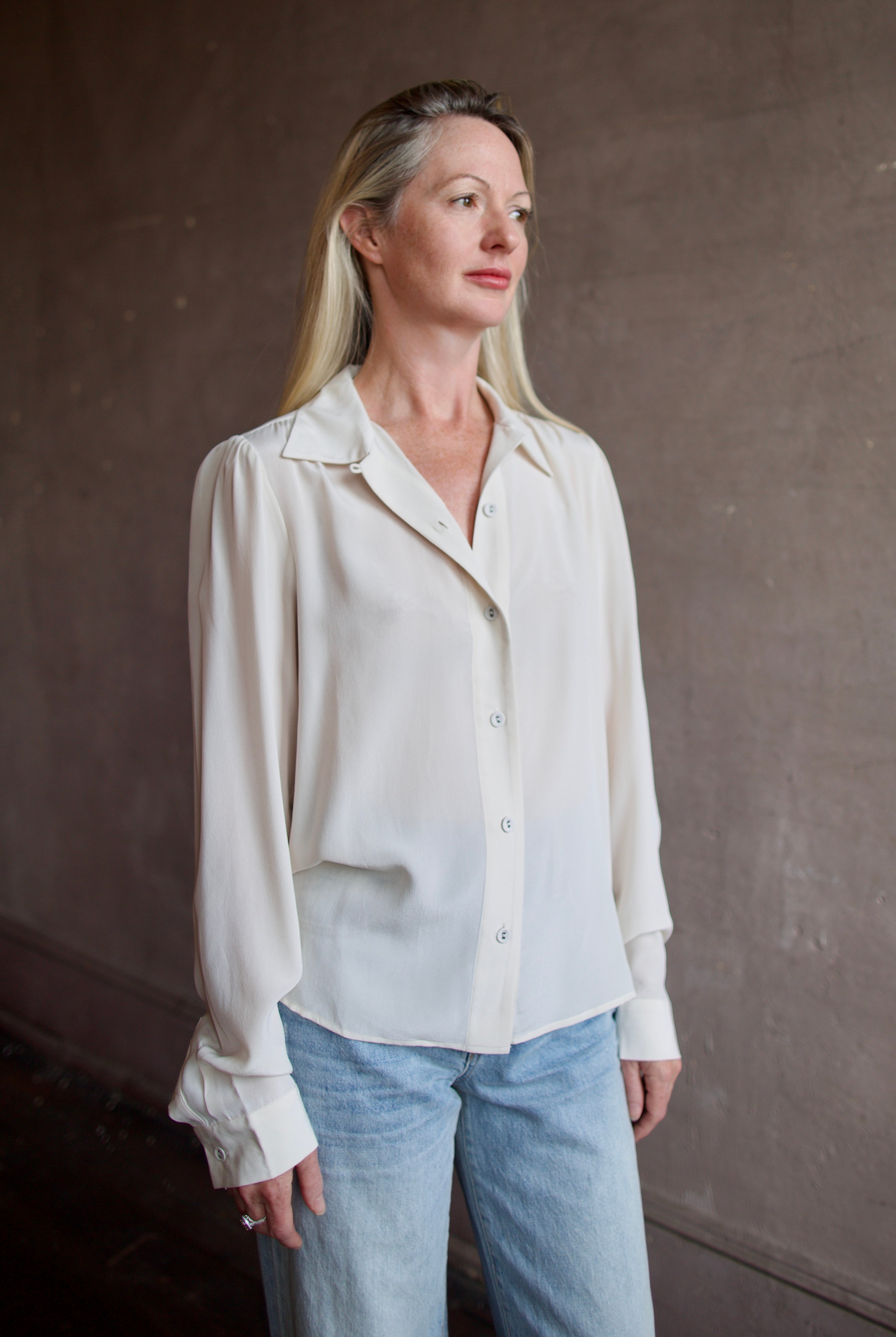 Model wearing a beige silk button down timeless blouse by Rachel Comey