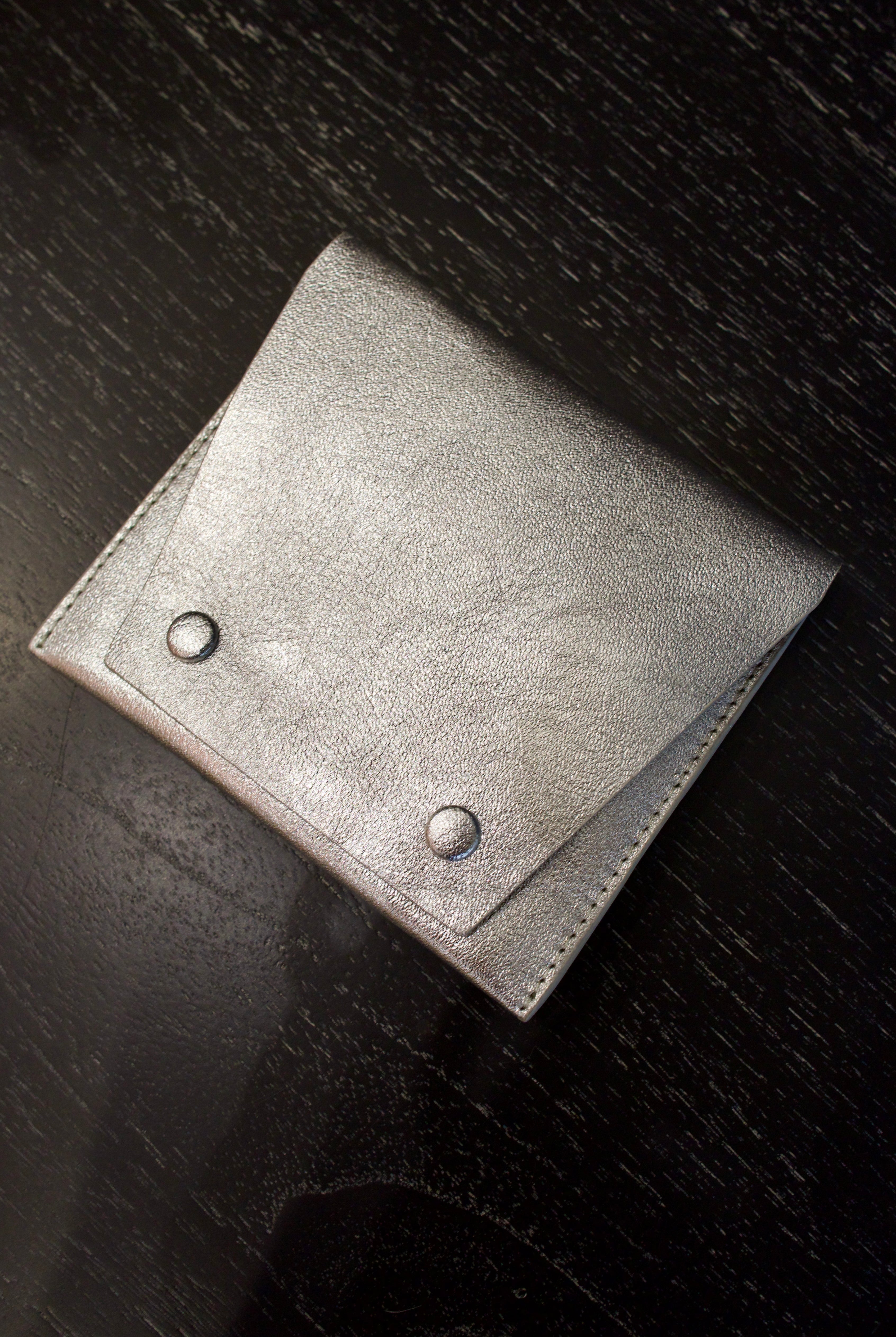 Photo of a silver metallic Rachel Comey leather wallet with two snap buttons closure