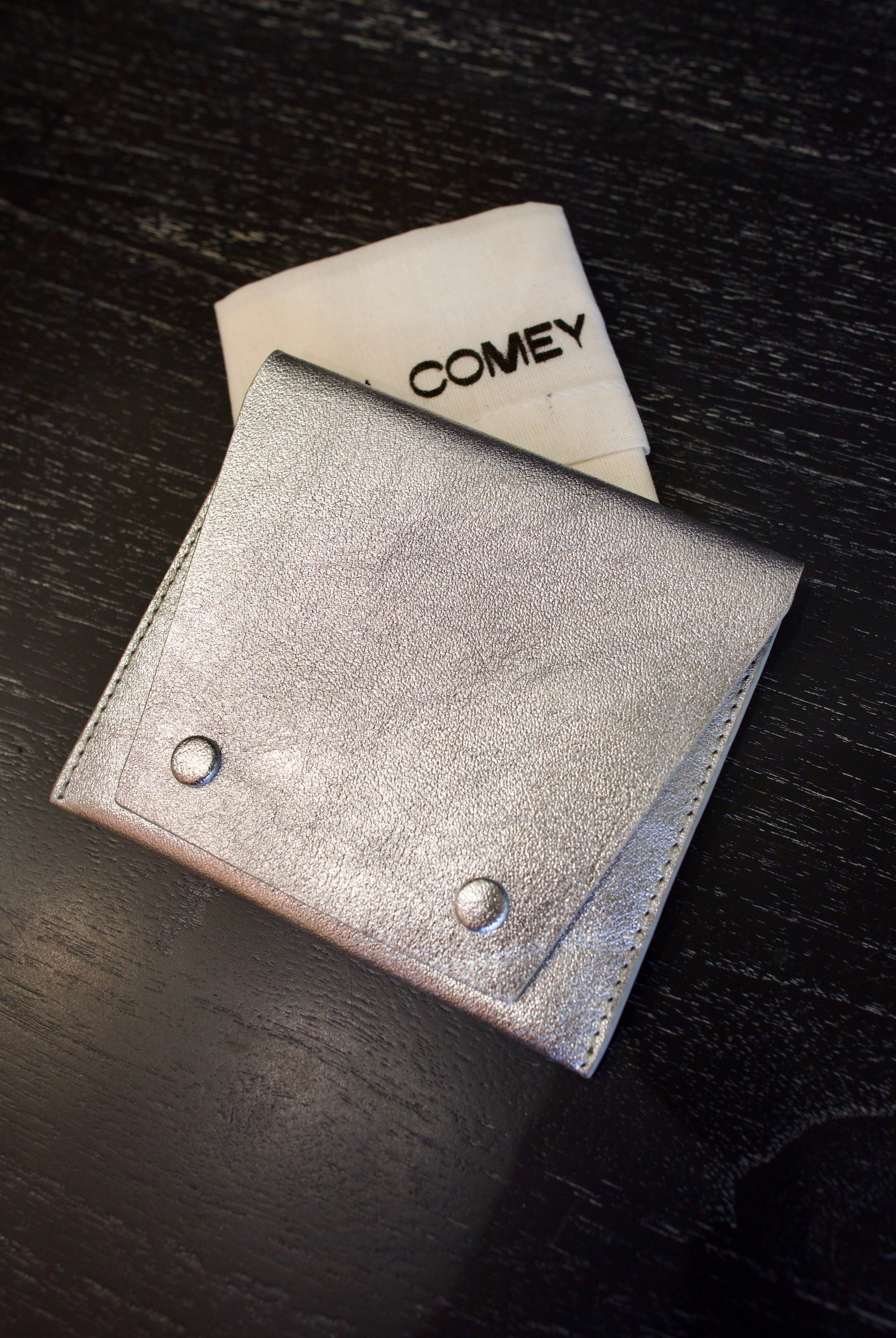 Photo of a silver metallic Rachel Comey leather wallet with two snap buttons closure