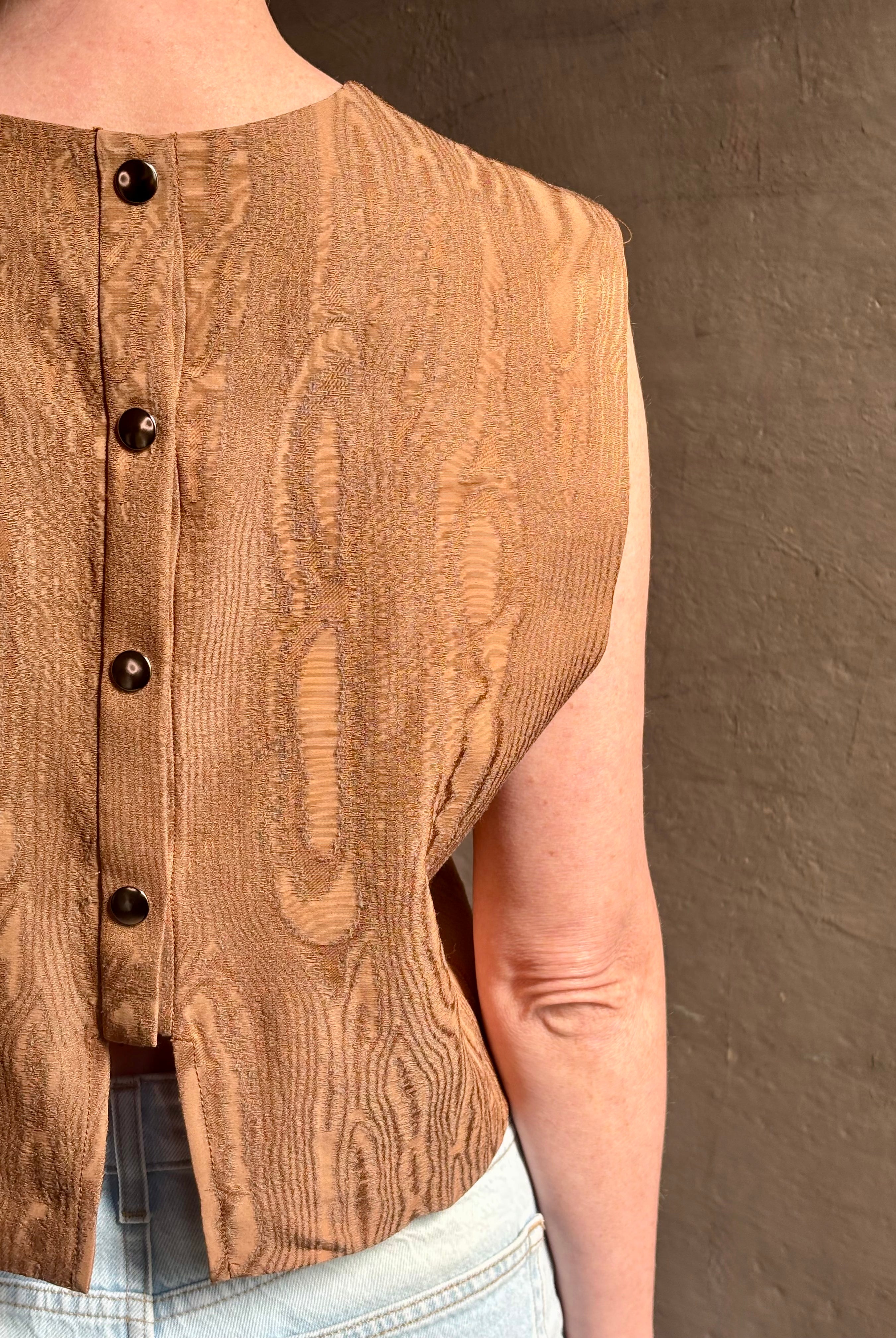 Mature woman wearing a brown faux boise patterned sleeveless viscose top by designer Rachel Comey with a crew neckline and button back closure