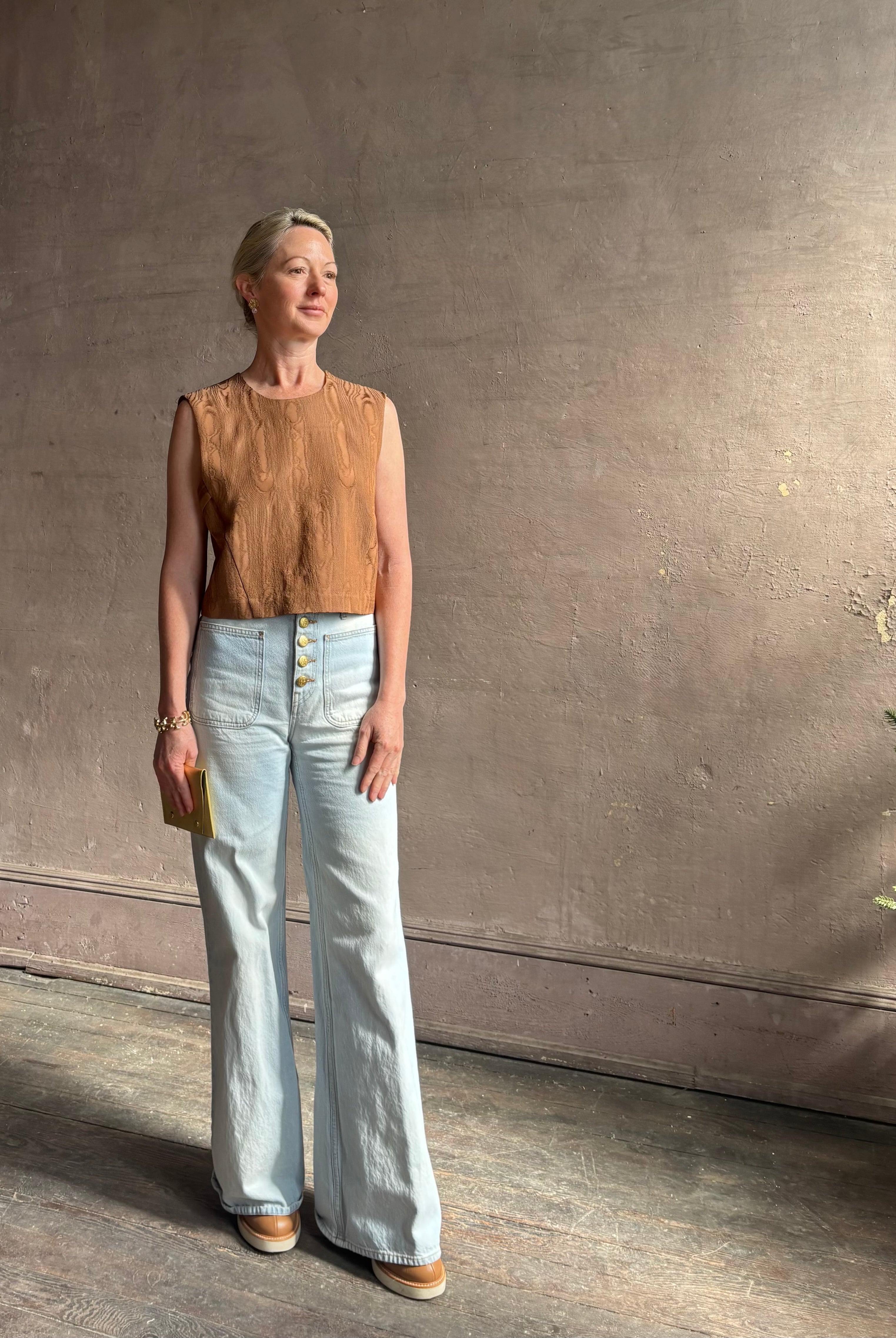 Mature woman wearing a brown faux boise patterned sleeveless viscose top by designer Rachel Comey with a crew neckline and button back closure