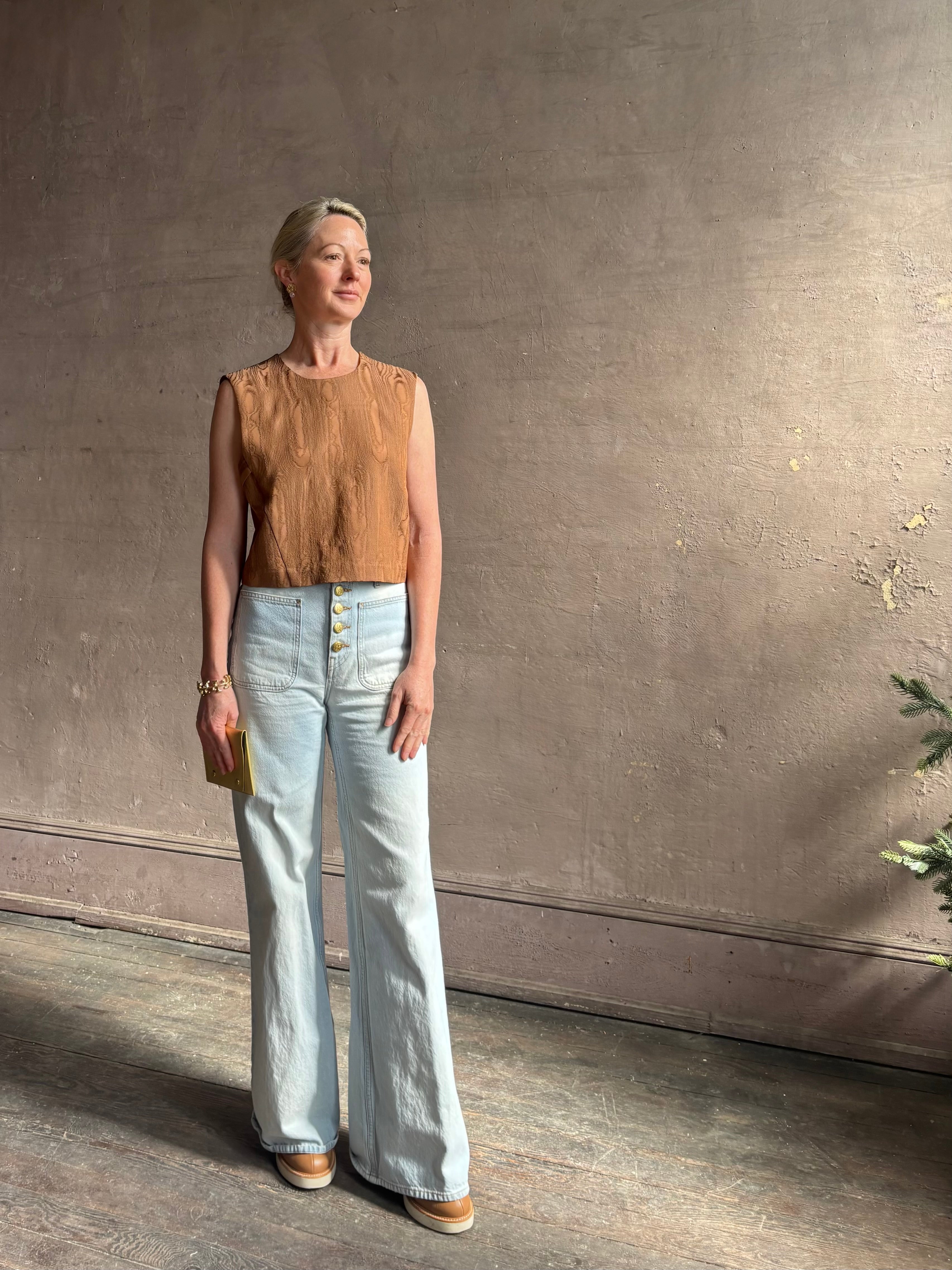 Mature woman wearing a brown faux boise patterned sleeveless viscose top by designer Rachel Comey with a crew neckline and button back closure