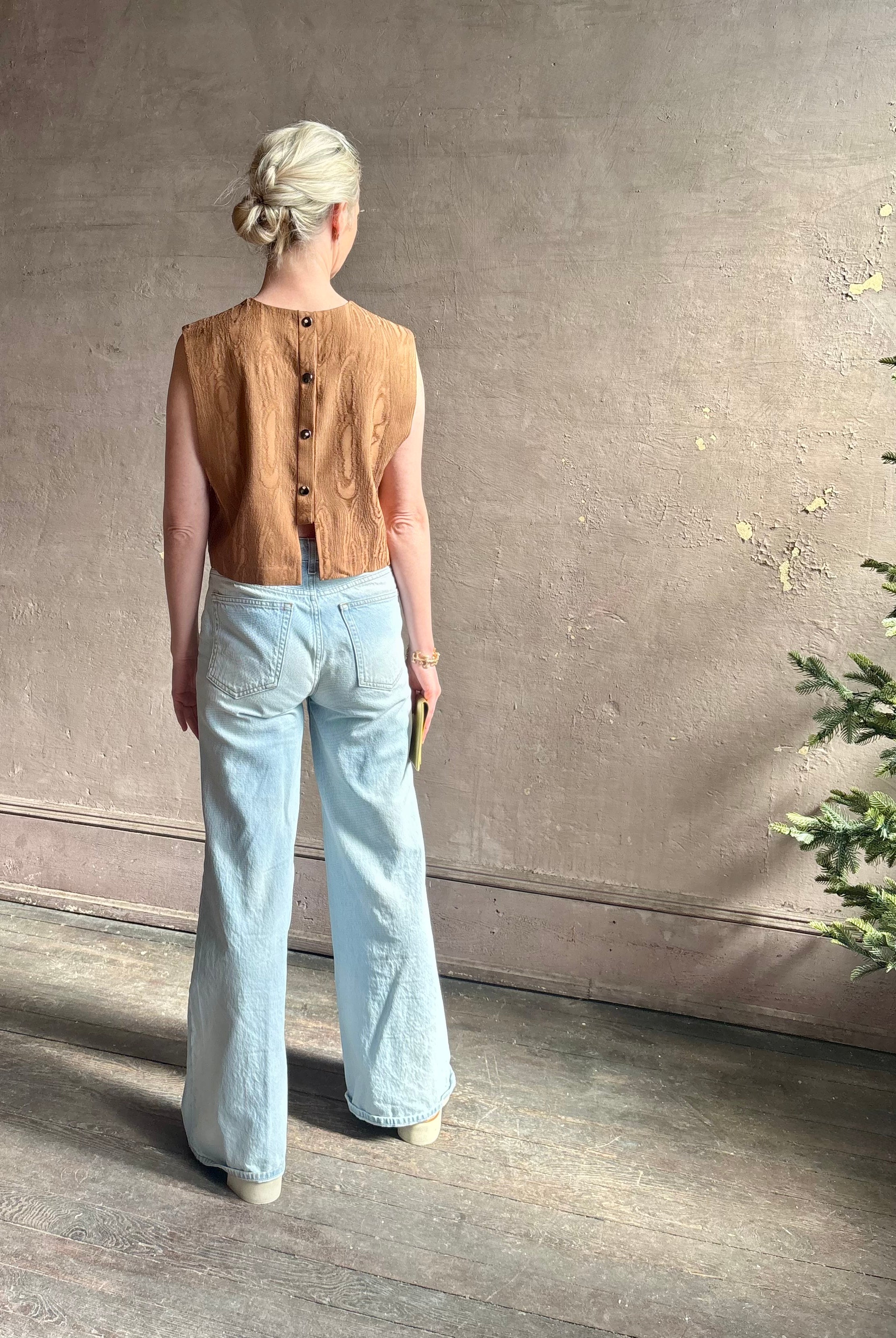 Mature woman wearing a brown faux boise patterned sleeveless viscose top by designer Rachel Comey with a crew neckline and button back closure