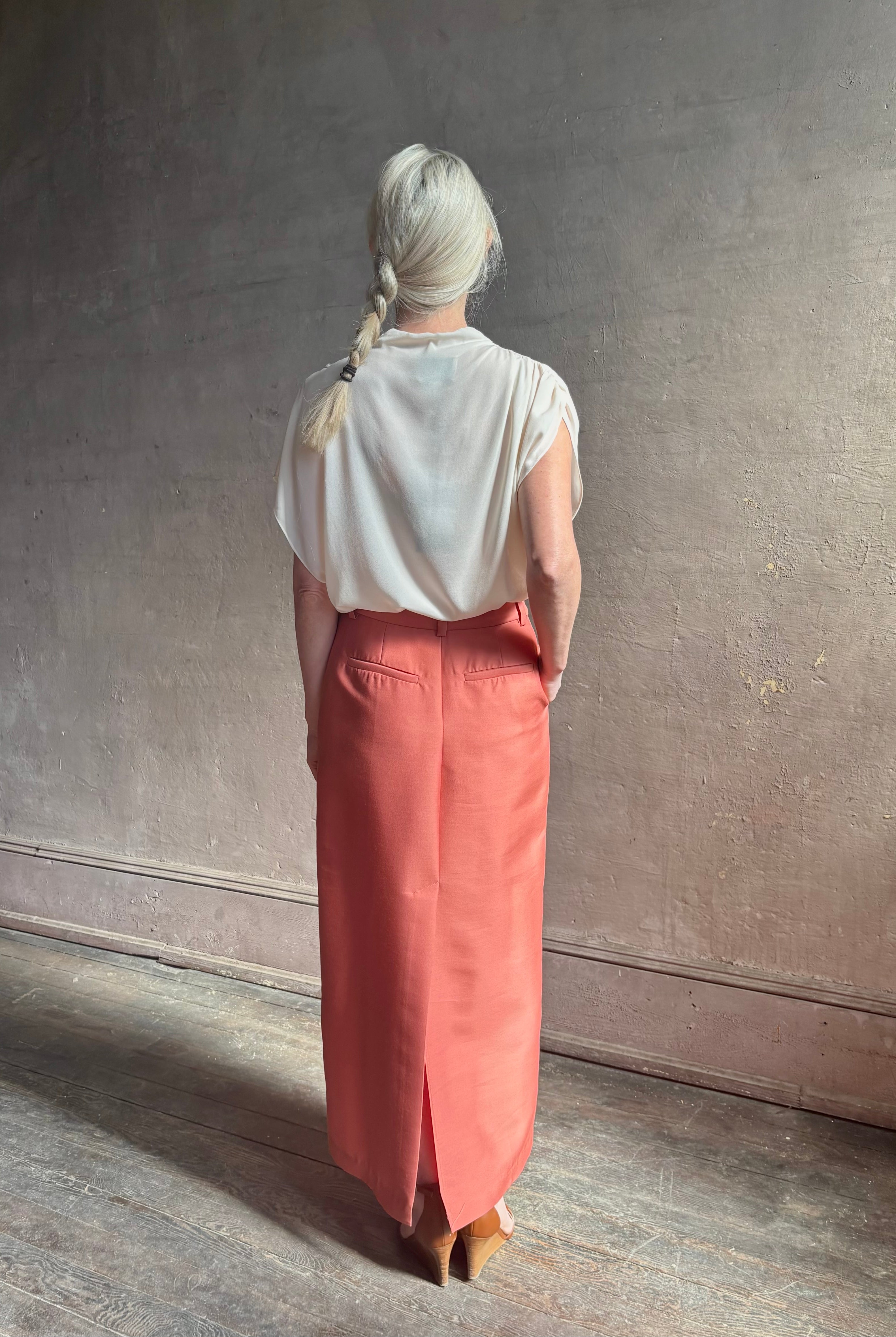 Mature woman wearing premium wool silk women's designer Rachel Comey Cosa maxi Skirt with tailored waistband, belt loops and back vent rendered in a vibrant warm pink hue
