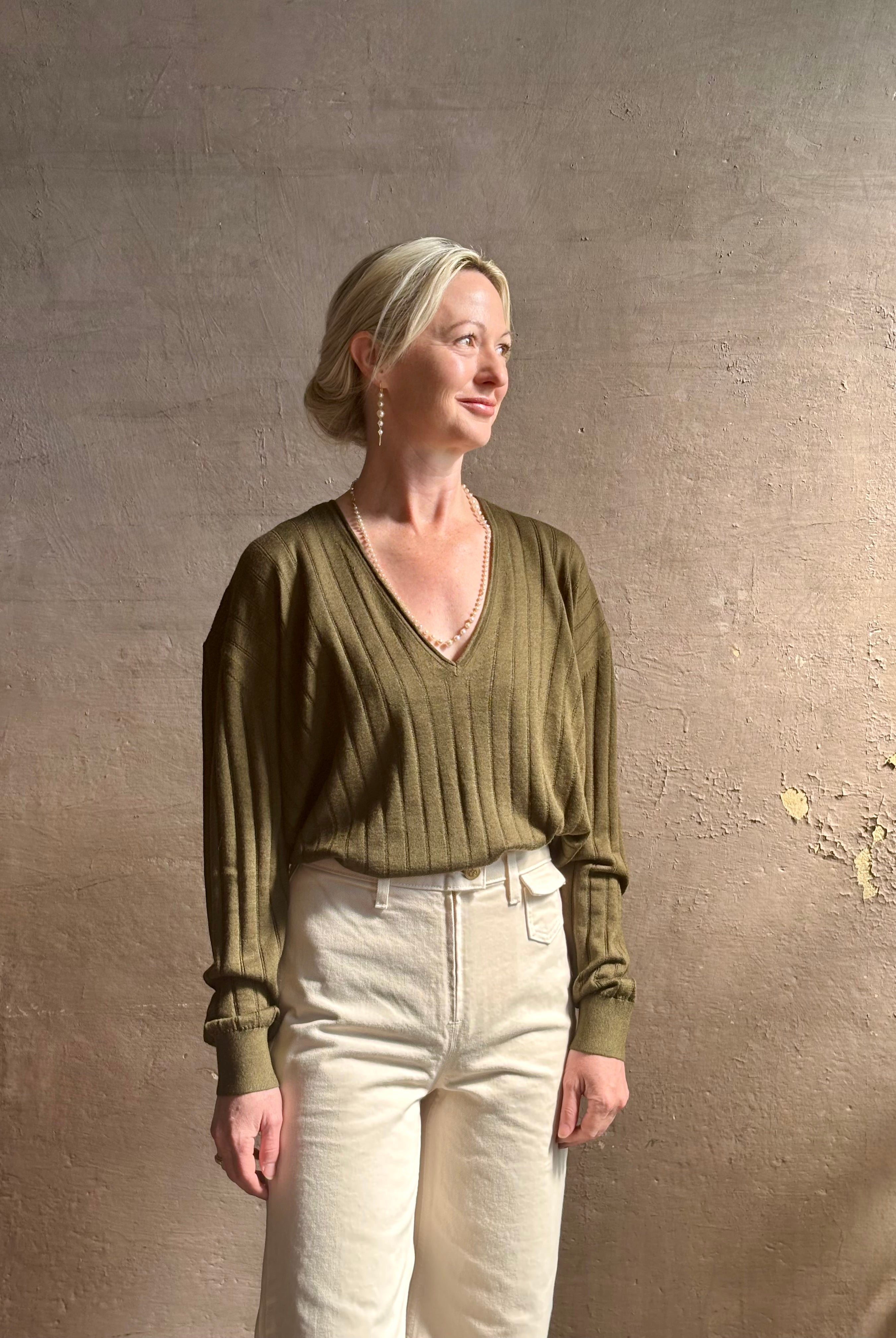 Mature woman wearing luxury Cashmere Silk Marion V-Neck designer Sweater by Rachel Comey in olive green with long sleeves and linear weave