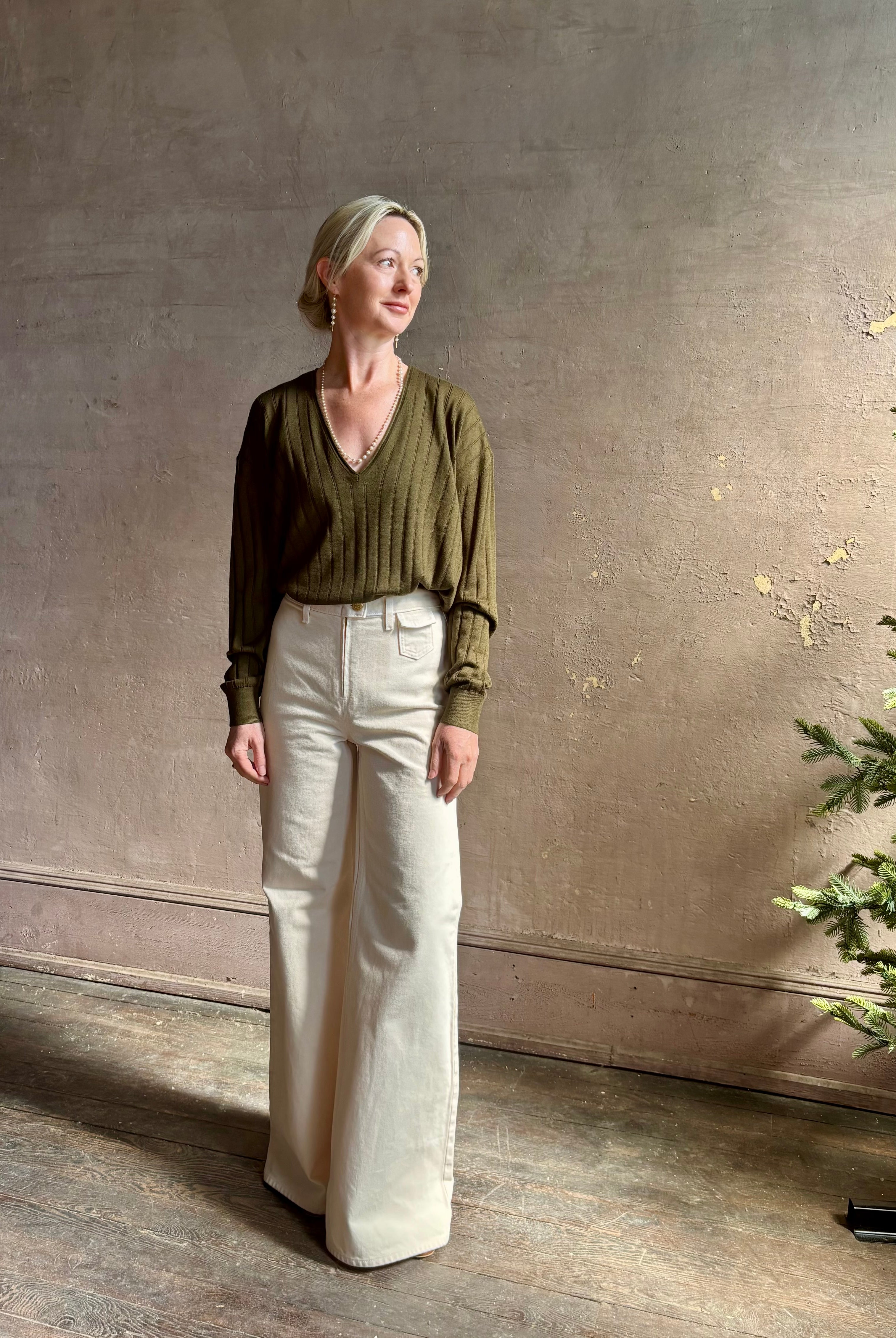 Mature woman wearing luxury Cashmere Silk Marion V-Neck designer Sweater by Rachel Comey in olive green with long sleeves and linear weave