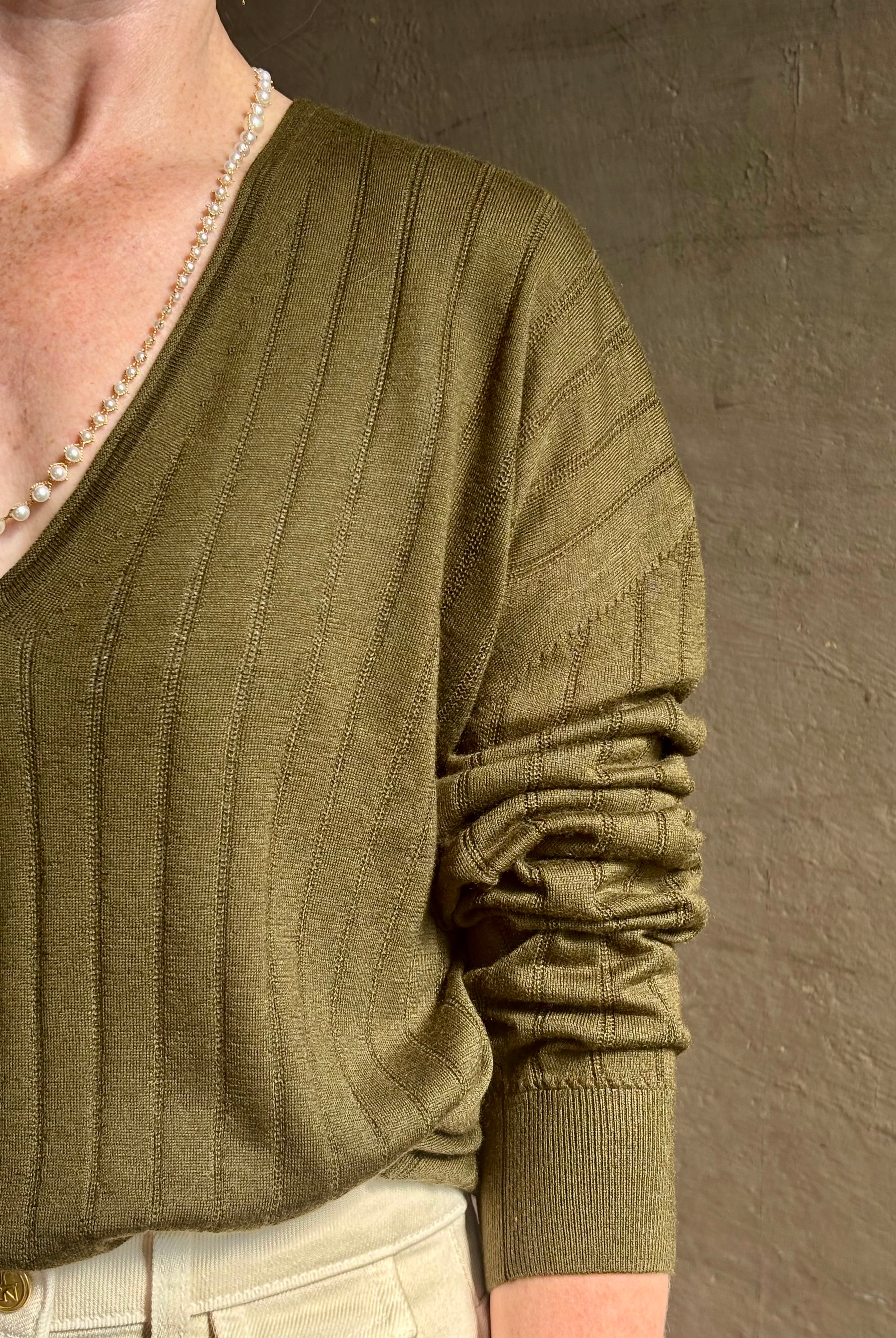 Mature woman wearing luxury Cashmere Silk Marion V-Neck designer Sweater by Rachel Comey in olive green with long sleeves and linear weave