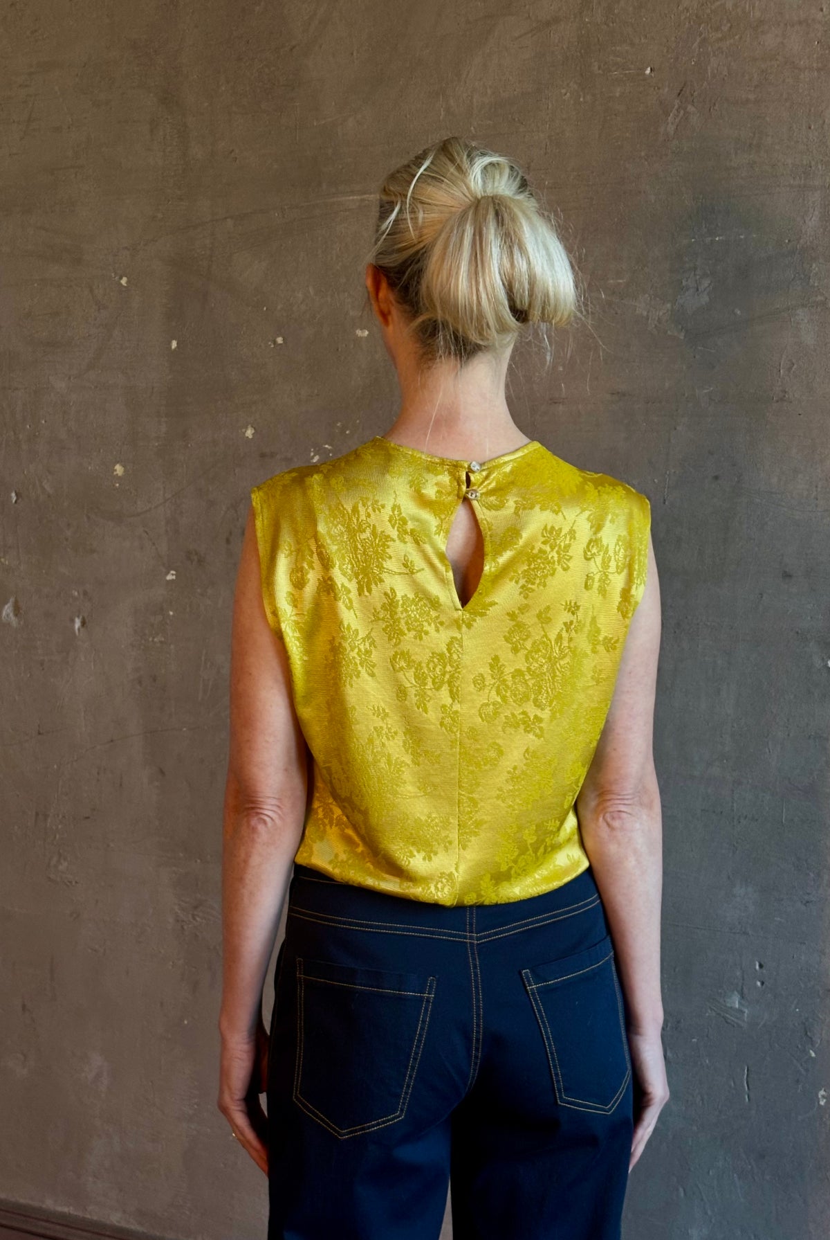Mature woman wearing Rachel Comey Primula Pique Knit Top in Mustard yellow waterfall front tone-on-tone jacquard floral made in the USA