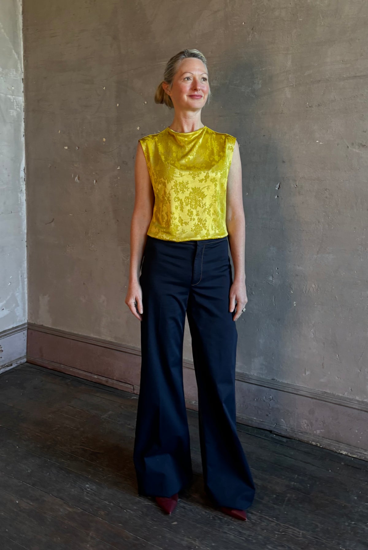 Mature woman wearing Rachel Comey Primula Pique Knit Top in Mustard yellow waterfall front tone-on-tone jacquard floral made in the USA