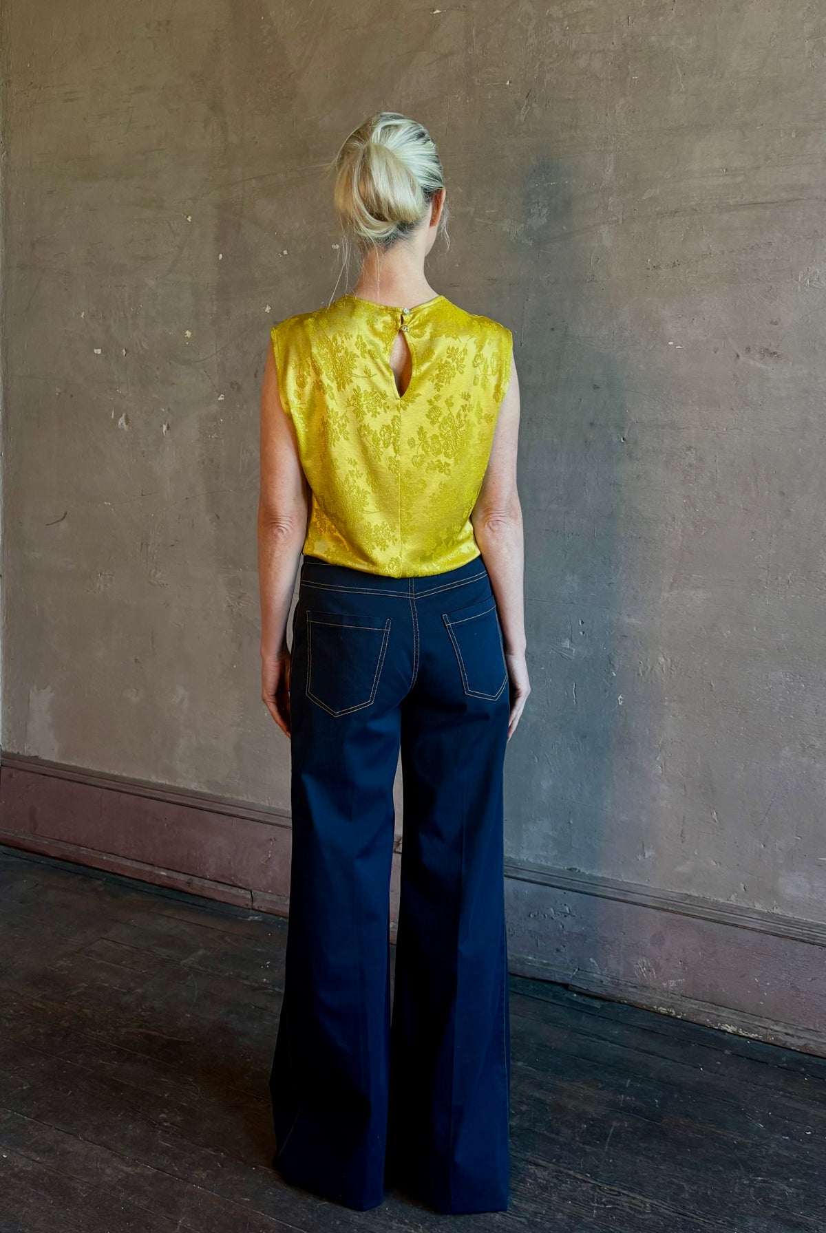 Mature woman wearing Rachel Comey Primula Pique Knit Top in Mustard yellow waterfall front tone-on-tone jacquard floral made in the USA