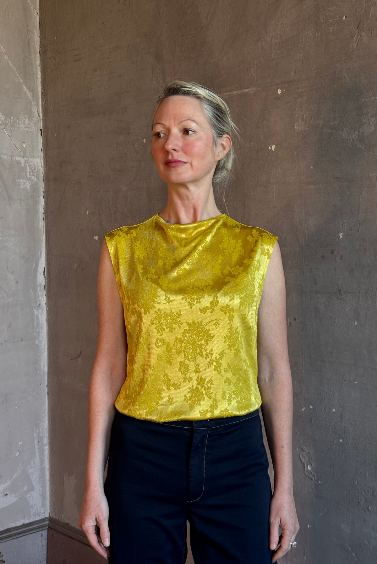 Mature woman wearing Rachel Comey Primula Pique Knit Top in Mustard yellow waterfall front tone-on-tone jacquard floral made in the USA