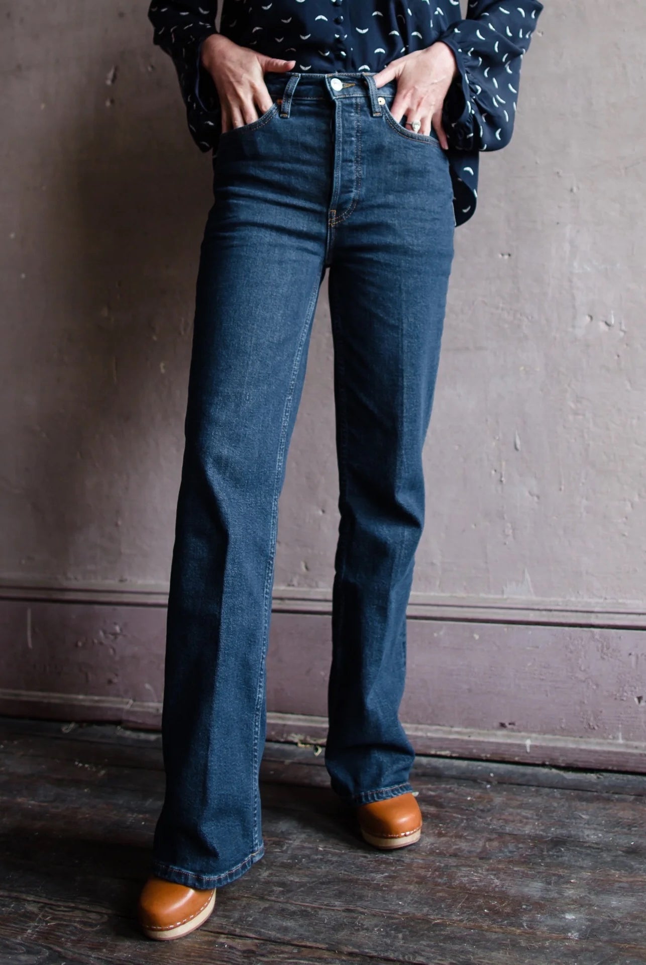 Image featuring a woman wearing the 70s Bootcut in Dark Rinse from Re/Done with a classic bootcut and long inseam with comfort stretch denim, a classic button fly, a finished hem.