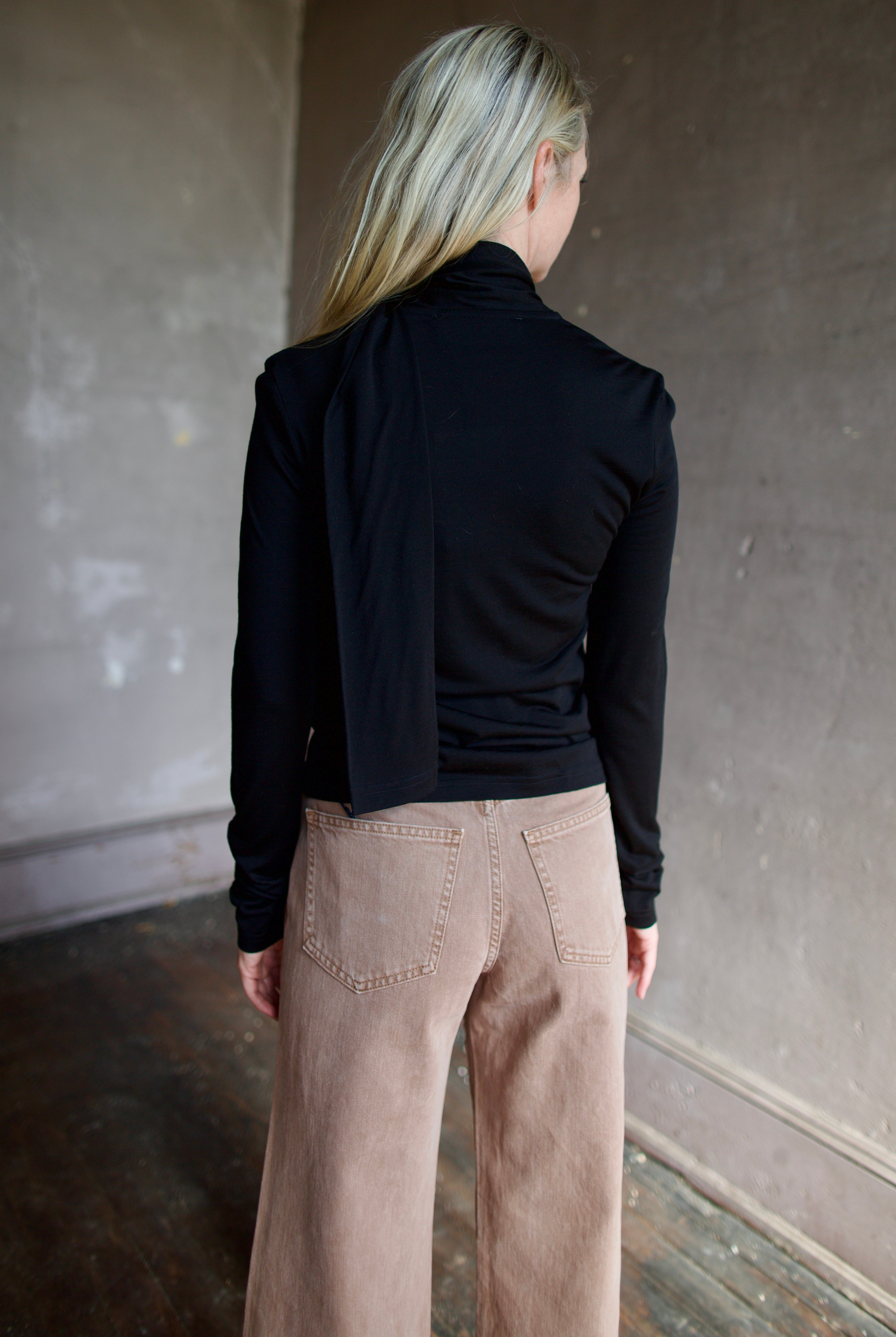 Model wearing a premium merino wool black top by luxury Amsterdam designer Rohe with integrated scarf for an quality elevated basic