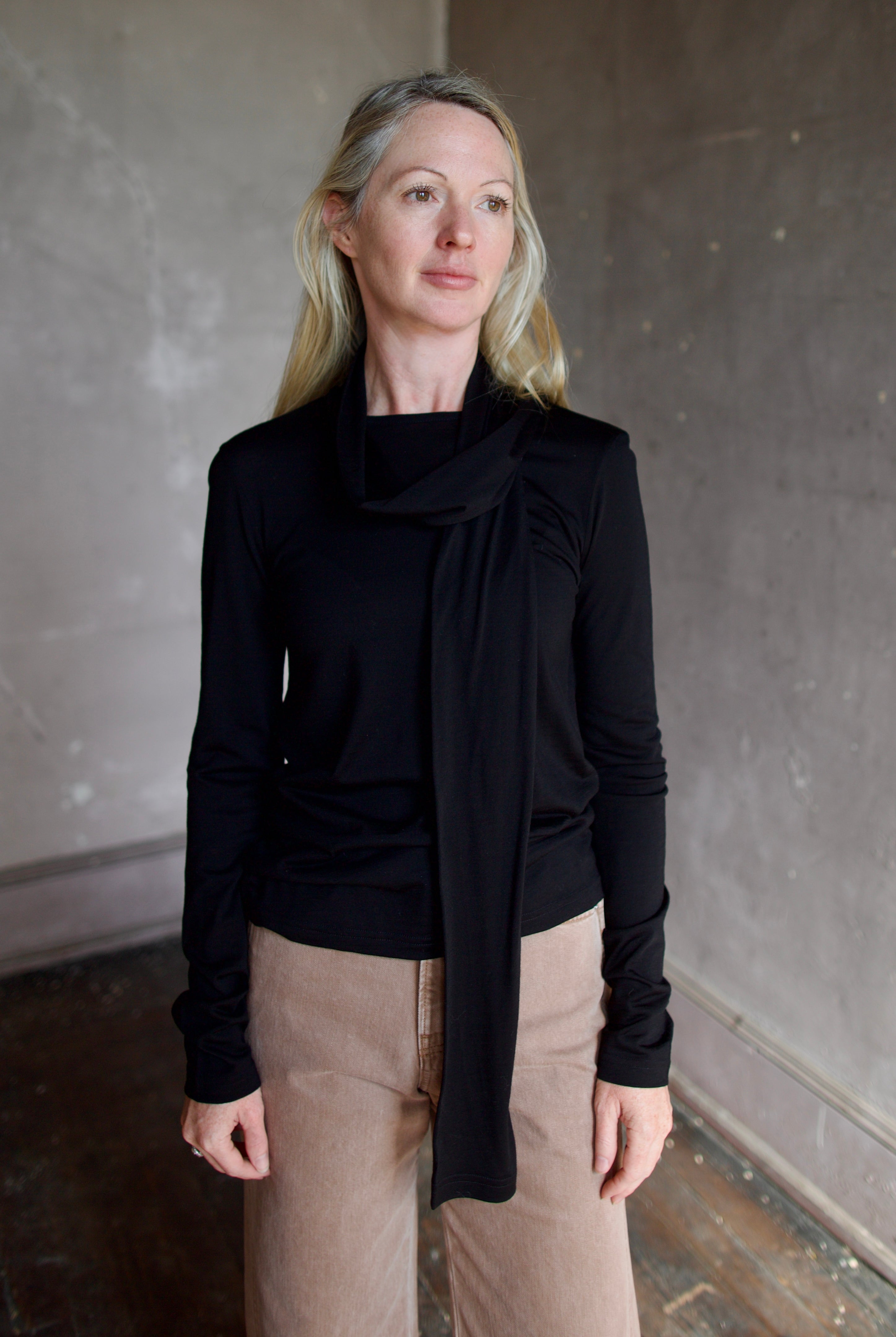 Model wearing a premium merino wool black top by luxury Amsterdam designer Rohe with integrated scarf for an quality elevated basic