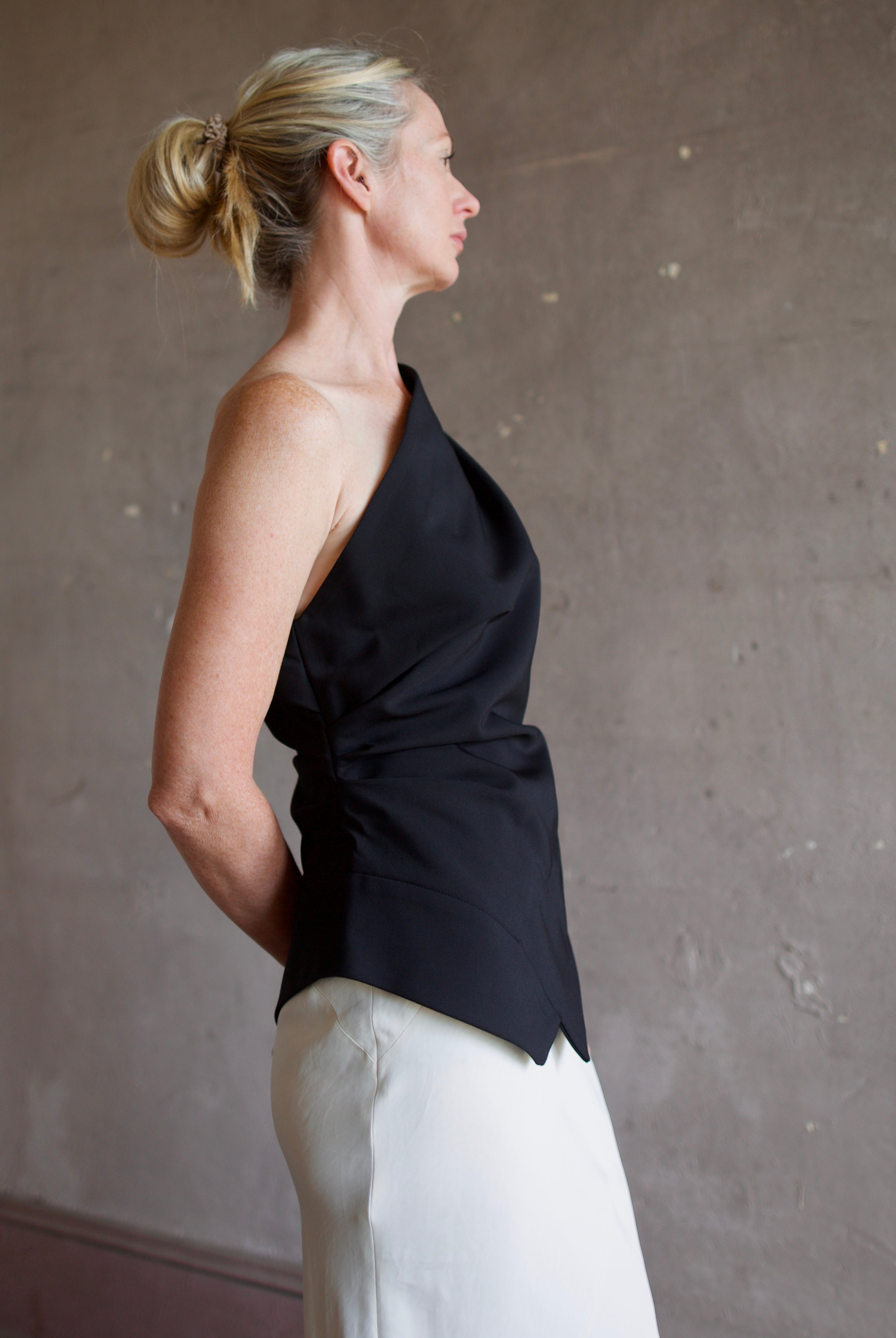 Model wearing sophisticated luxury modern designer brand Rohe flattering off shoulder lapel top in black