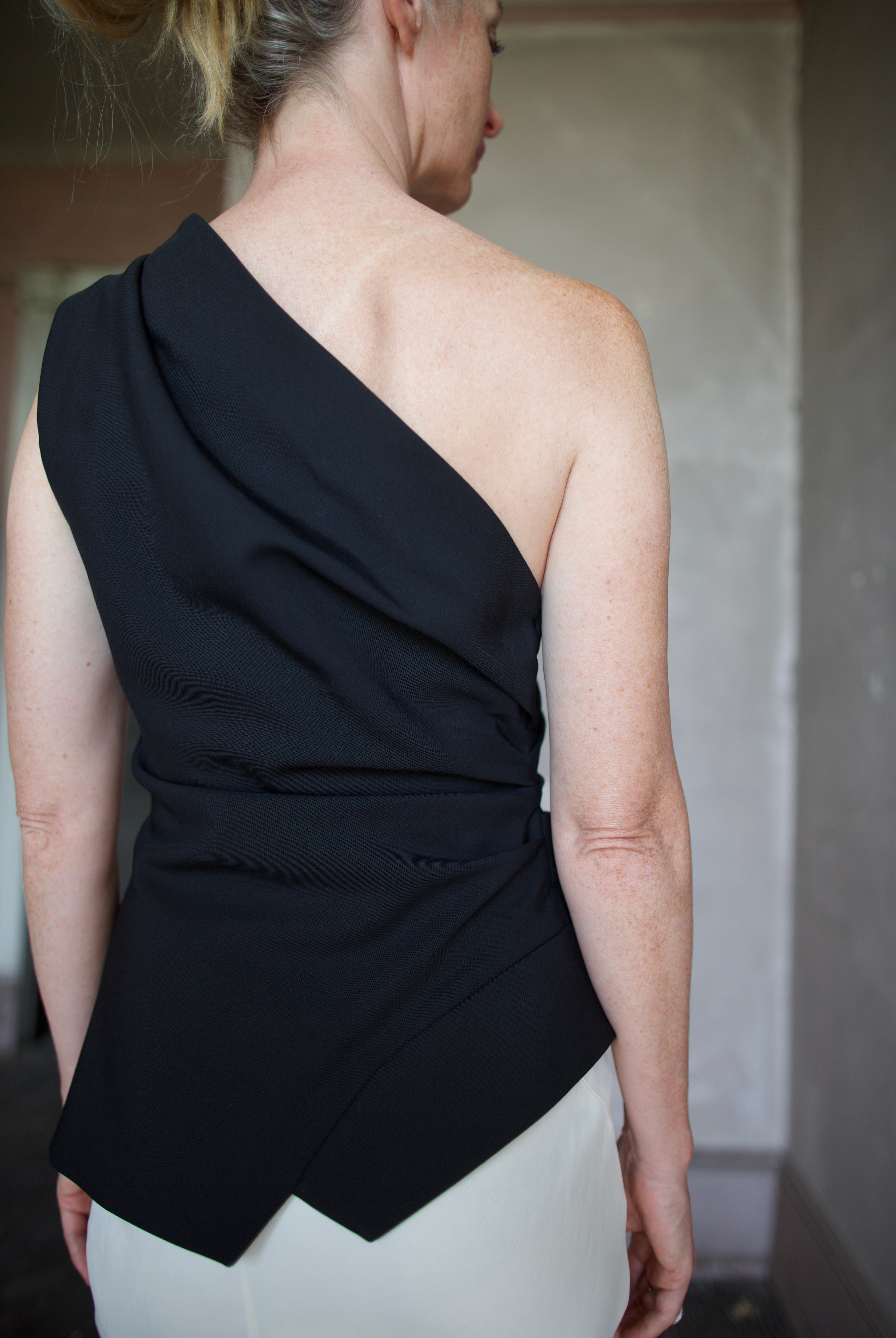 Model wearing luxury modern designer brand Rohe flattering off shoulder lapel top in black