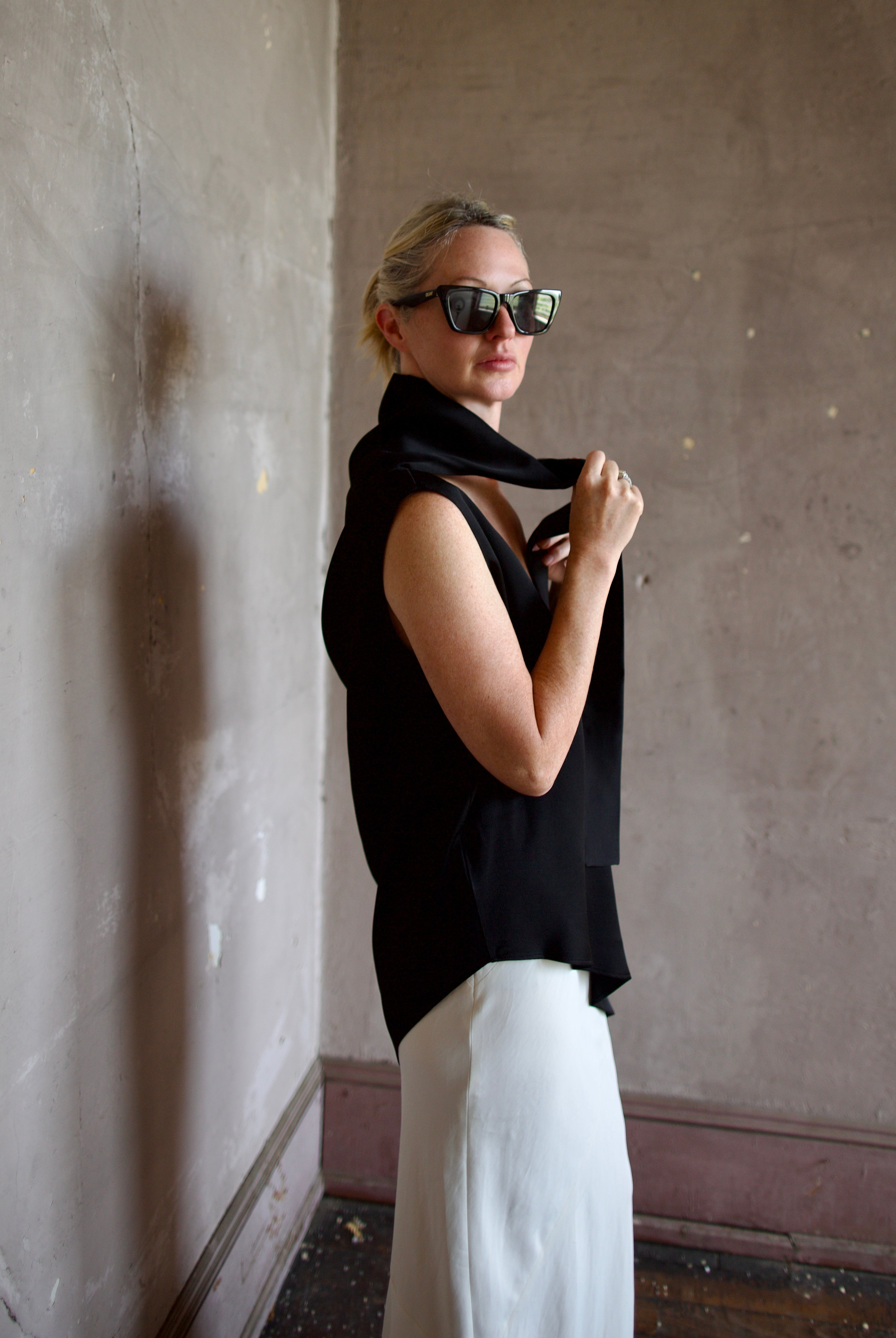 Model wearing black sleeveless satin top with expertly crafted draping and attached tie by luxury modern designer Rohe