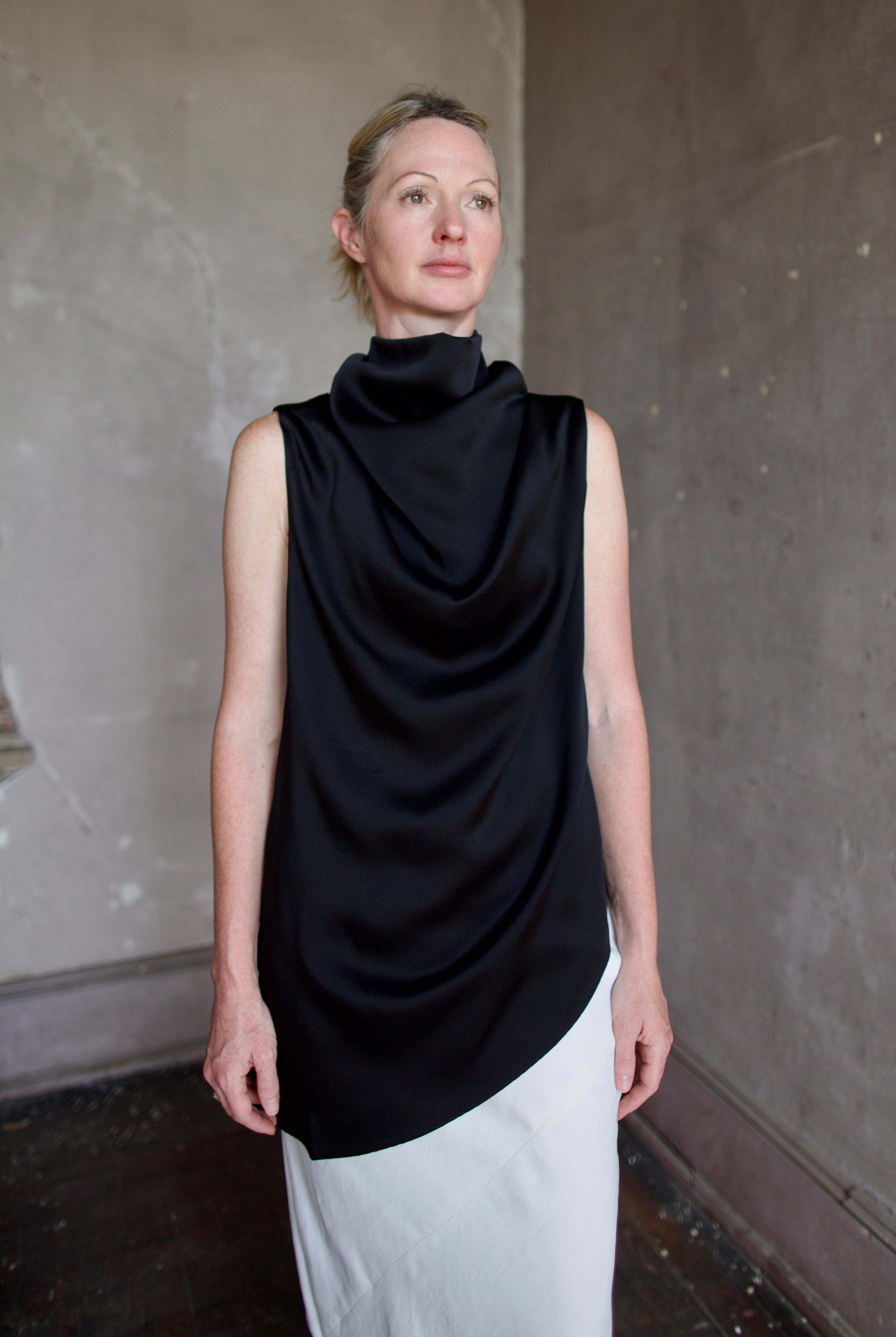 Model wearing black sleeveless satin top with expertly crafted draping by luxury modern designer Rohe