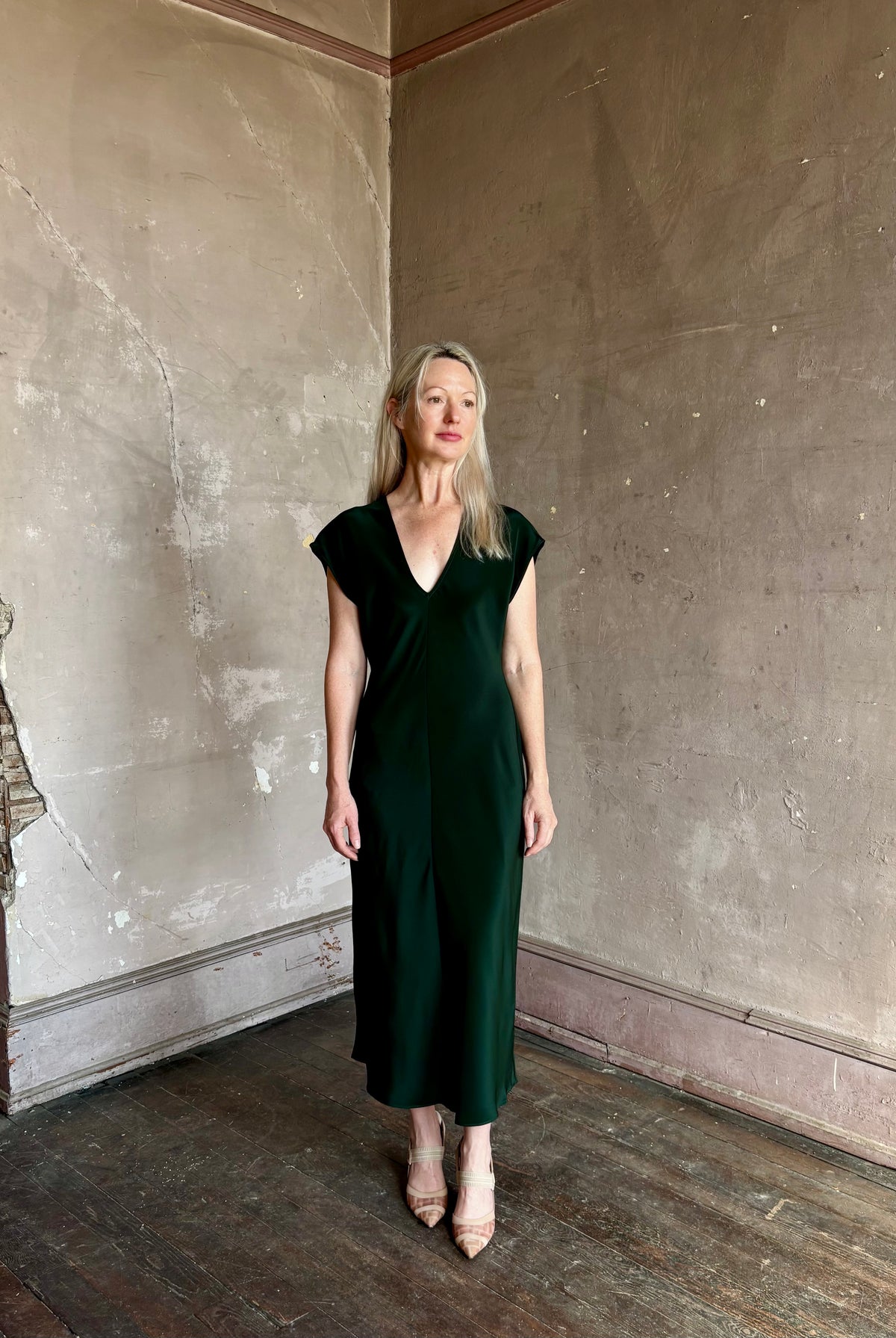 Mature woman wearing Sablyn Inez draped silk V-neck dark green midi dress with short cap sleeves made in USA