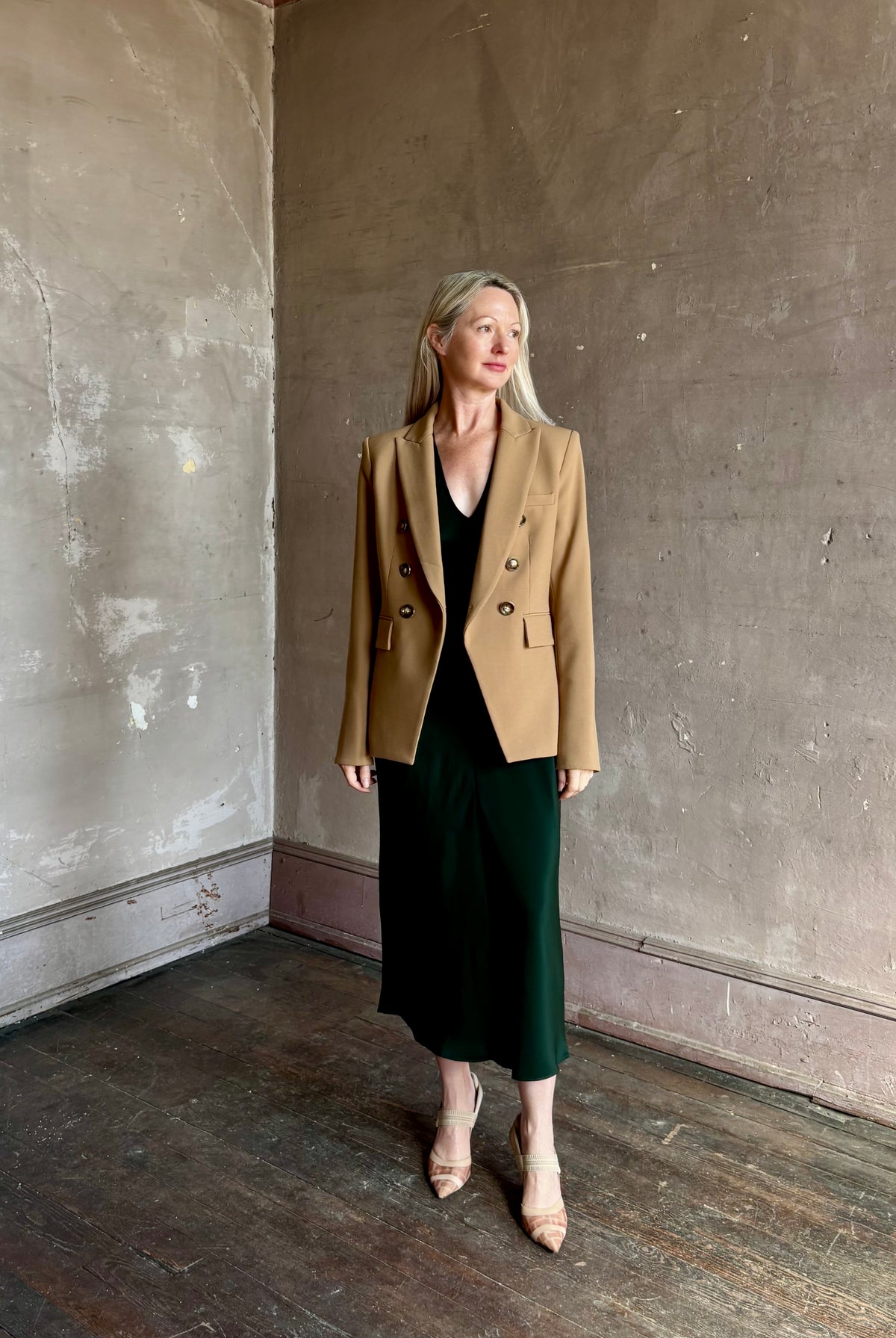 Mature woman wearing Sablyn Inez draped silk V-neck dark green midi dress with short cap sleeves made in USA