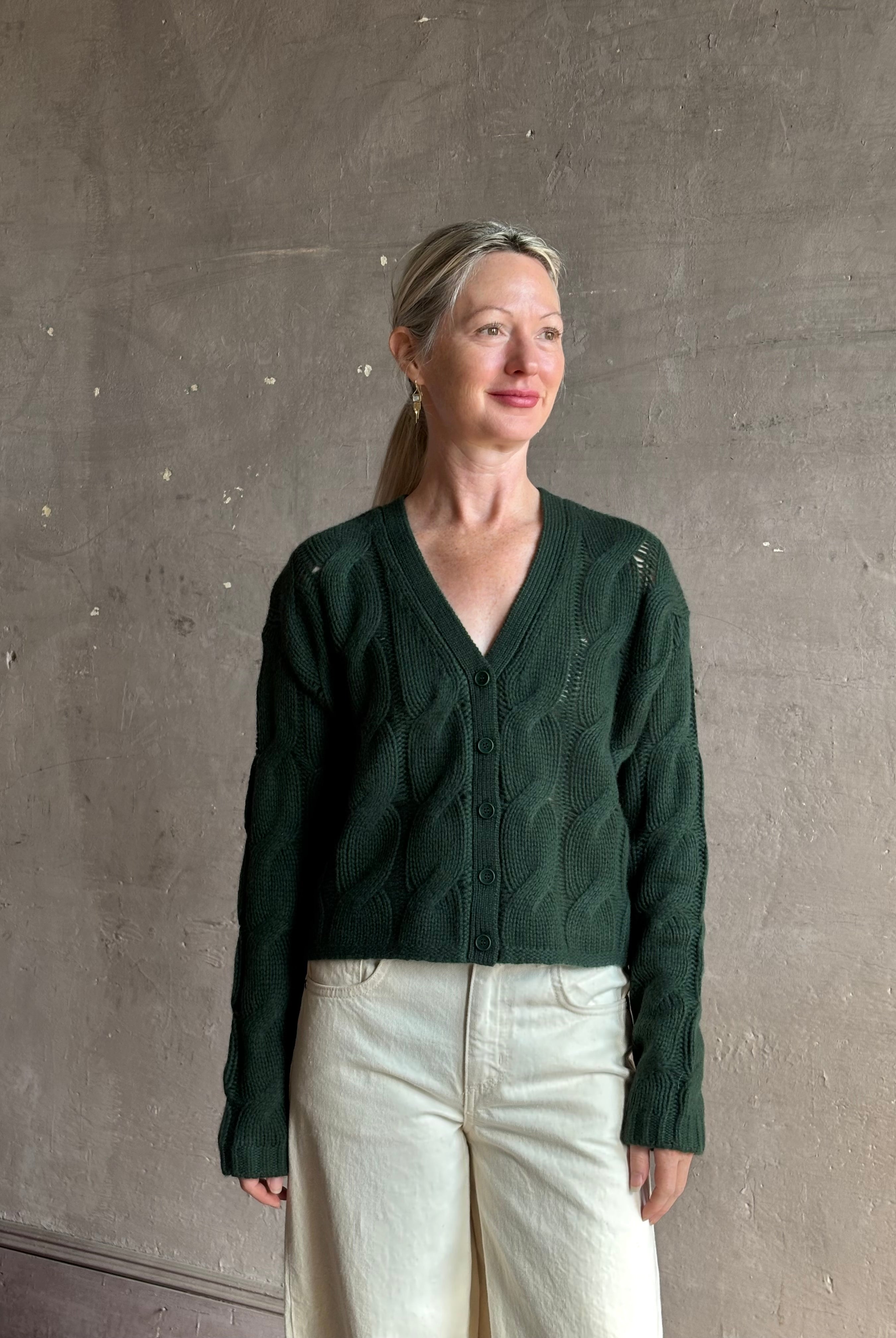 Mature woman wearing Sablyn Jolie dark green V-neck cropped cable-knit long sleeve cashmere cardigan sweater