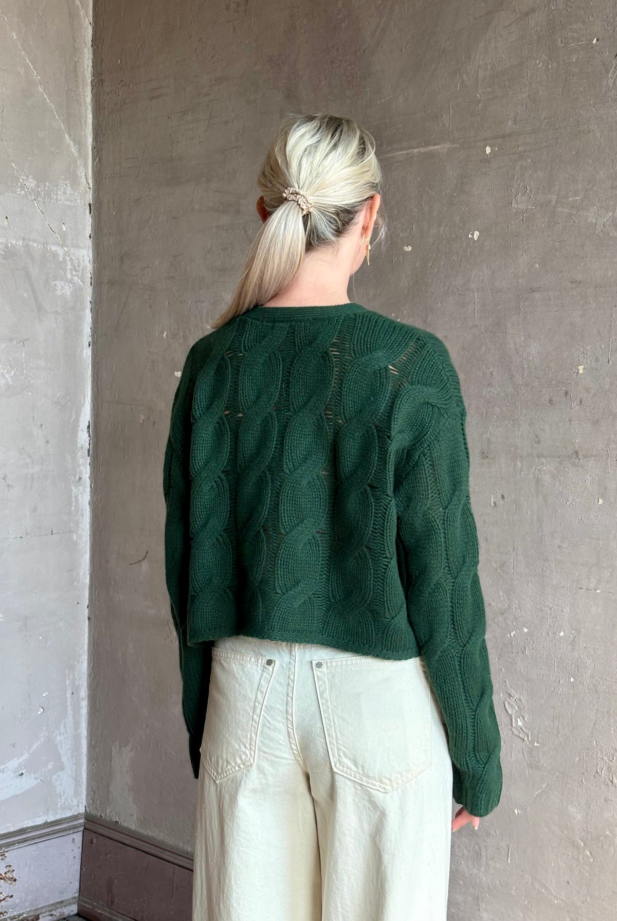Mature woman wearing Sablyn Jolie dark green V-neck cropped cable-knit button front long sleeve cashmere cardigan