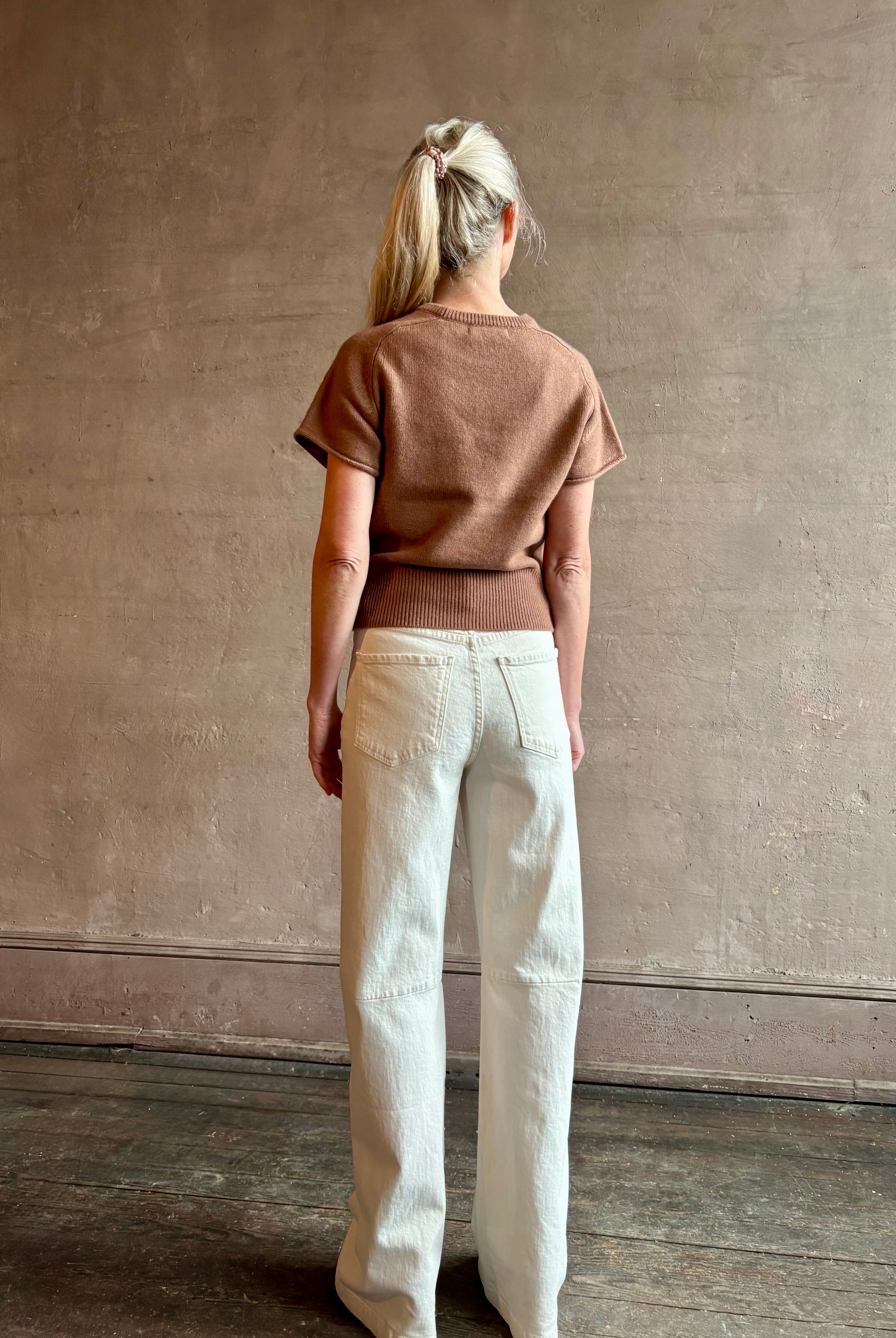 Woman wearing SABLYN Jones Saddle Raglan Cashmere Sweater in Prairie Sand with short sleeves and tailored waistband