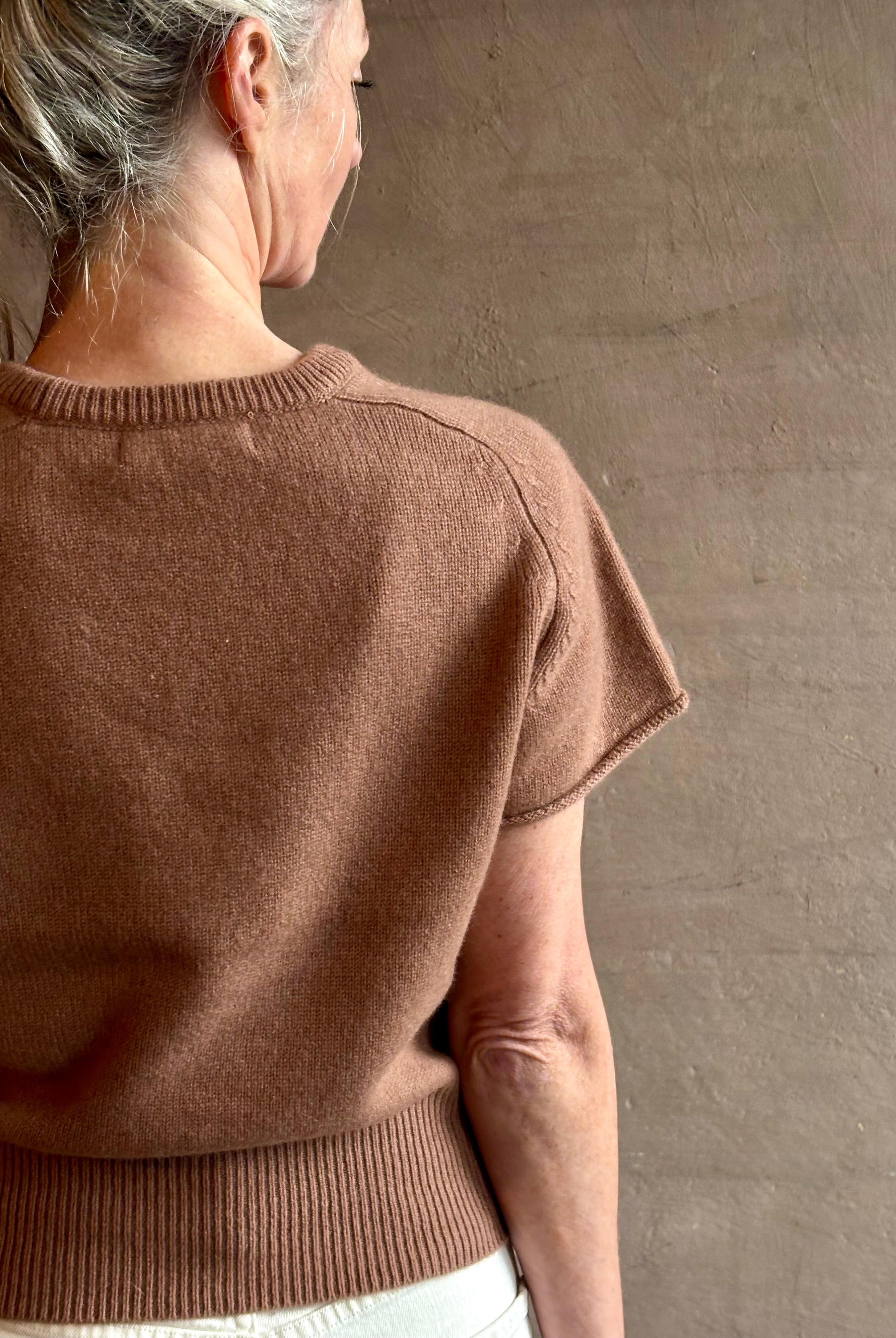 Woman wearing elegant luxury brand SABLYN Jones Saddle Raglan Cashmere Sweater in a neutral copper tone