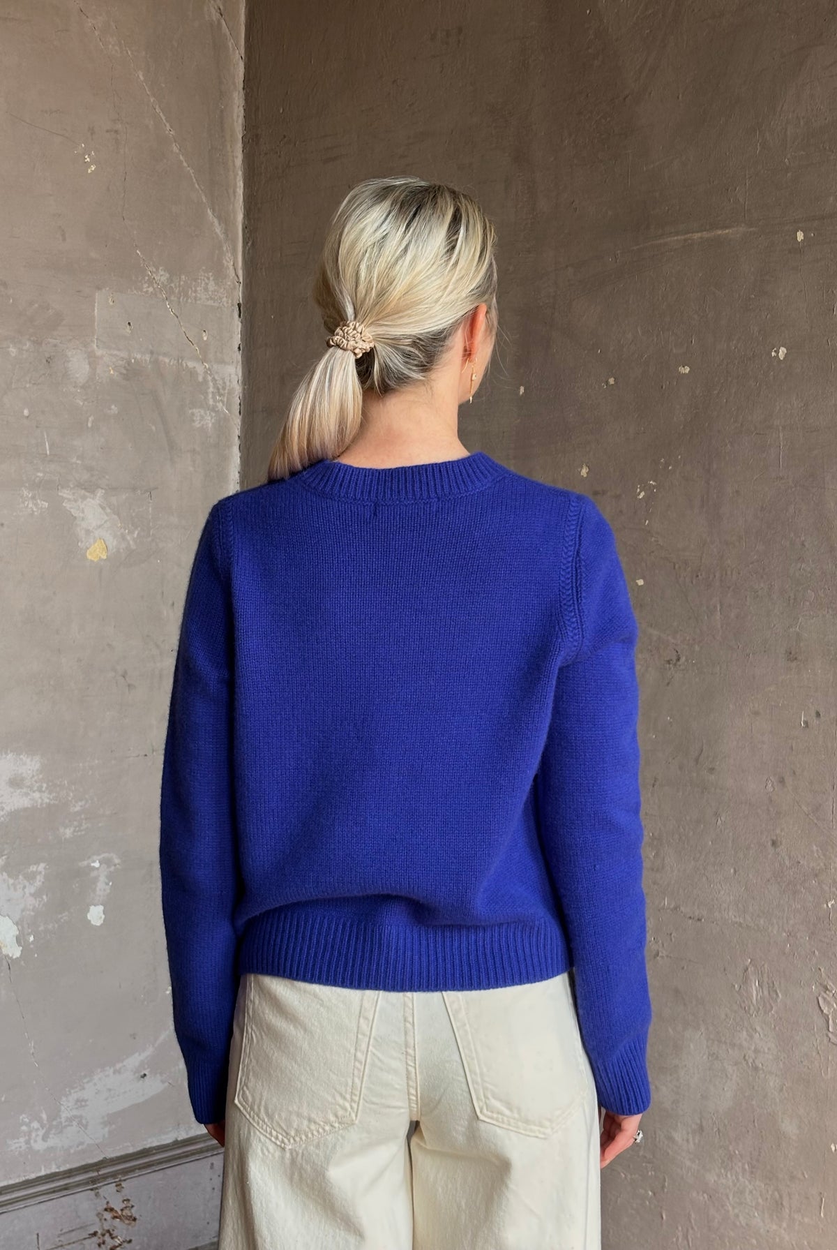 Mature woman wearing a vibrant cobalt blue Sablyn crewneck knit shrunken crewneck long sleeve cashmere sweater