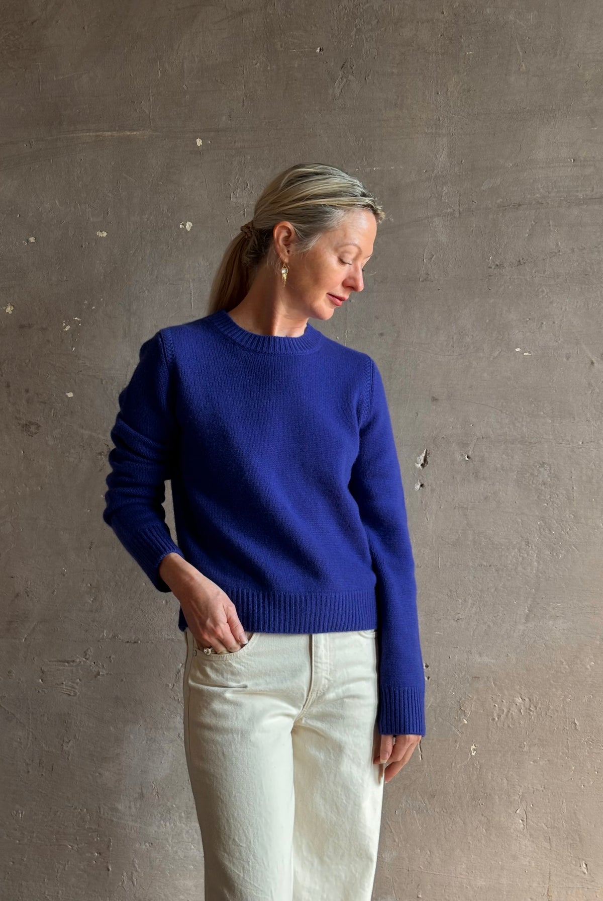 Mature woman wearing a vibrant cobalt blue Sablyn crewneck knit shrunken crewneck long sleeve cashmere sweater