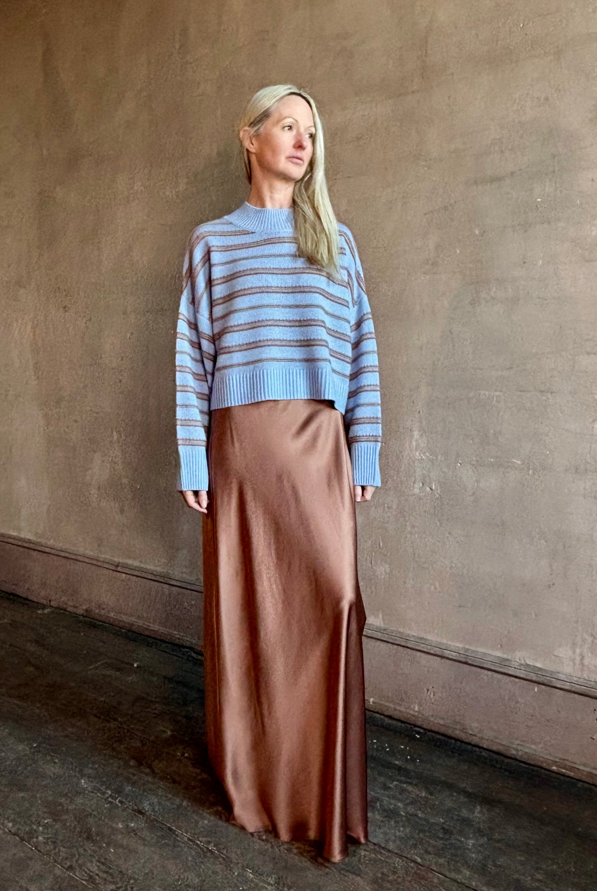 Woman wearing SABLYN Wells B Cropped Pullover Sweater in a french blue background and copper stripe