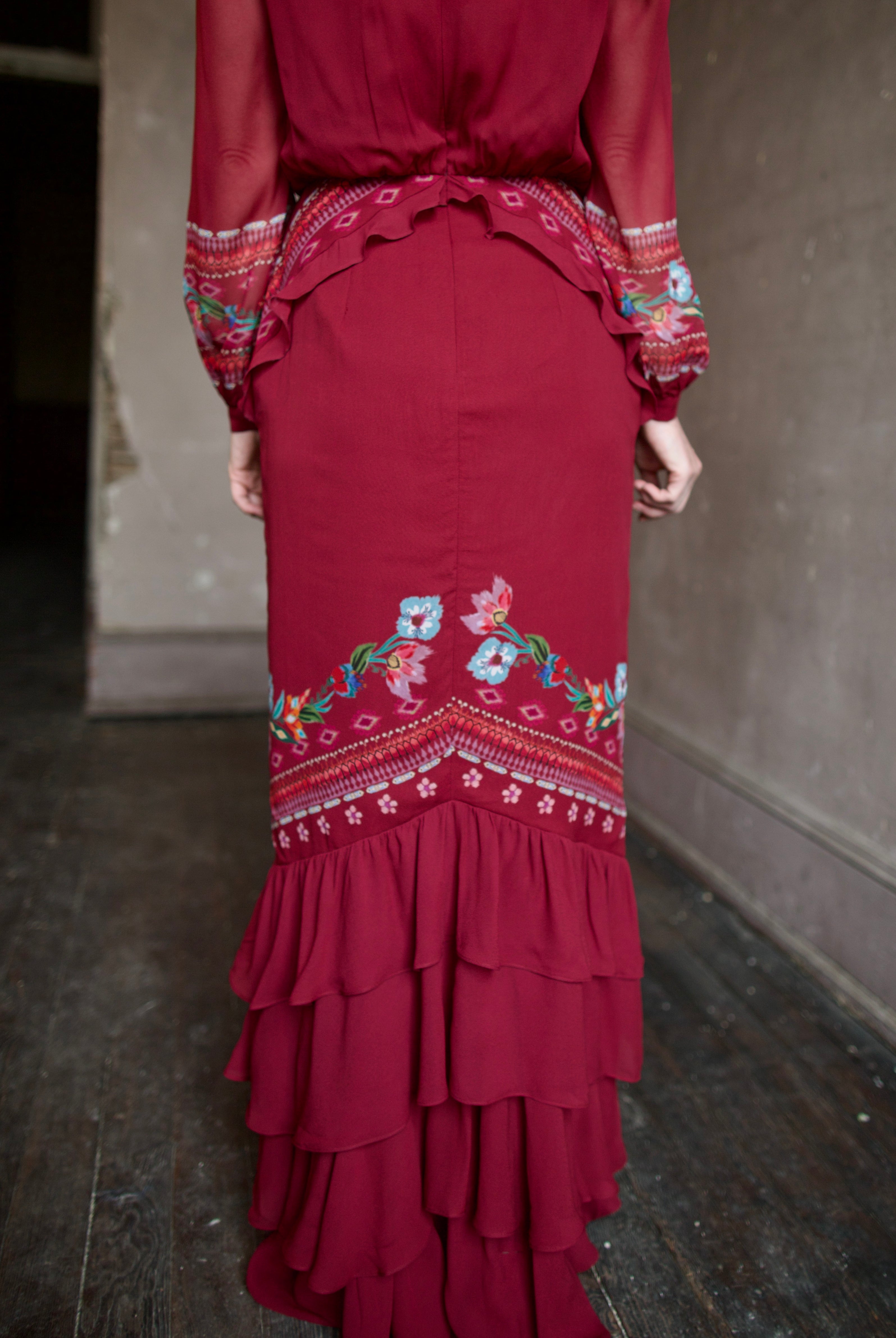 Mature woman wearing sophisticated Saloni Isa Long-C silk burgundy maxi Dress in Cordia Vines with long sleeves, delicate ruffle details and intricate floral pattern