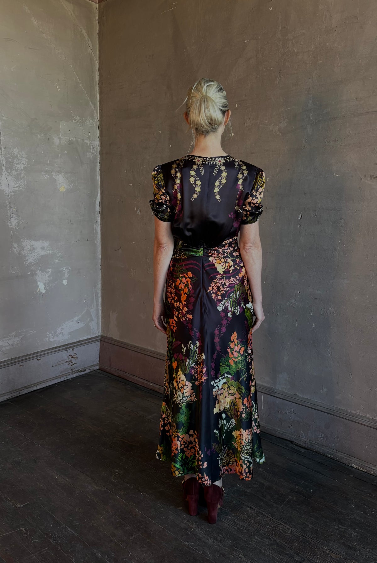 Mature woman wearing Saloni's Gwen C Dress in Equinox Plmt silk blend fit-and-flare silhouette cummerbund waist. Botanical, structured occasion elegance.