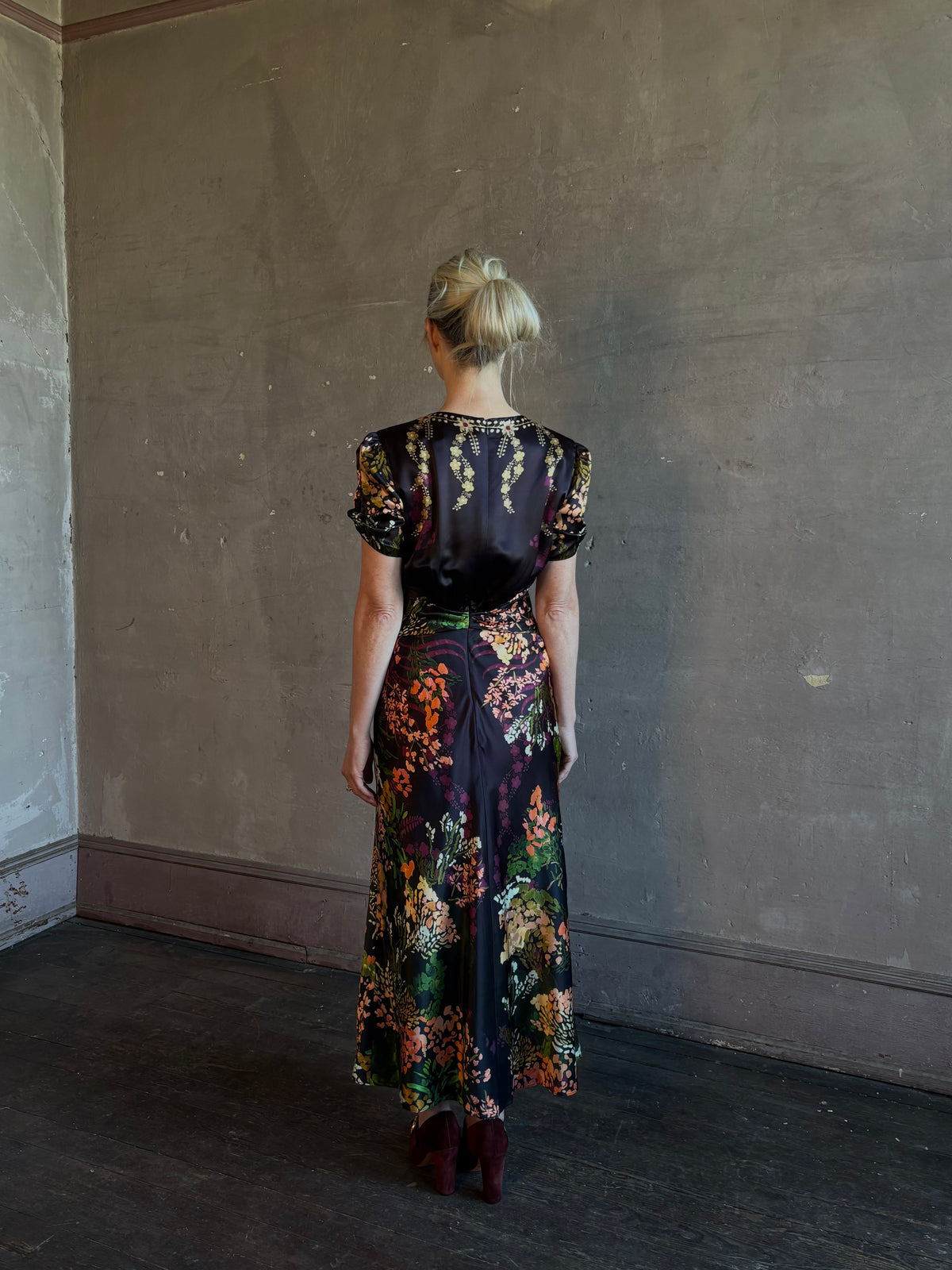 Mature woman wearing Saloni's Gwen C Dress in Equinox Plmt silk blend fit-and-flare silhouette cummerbund waist. Botanical, structured occasion elegance.