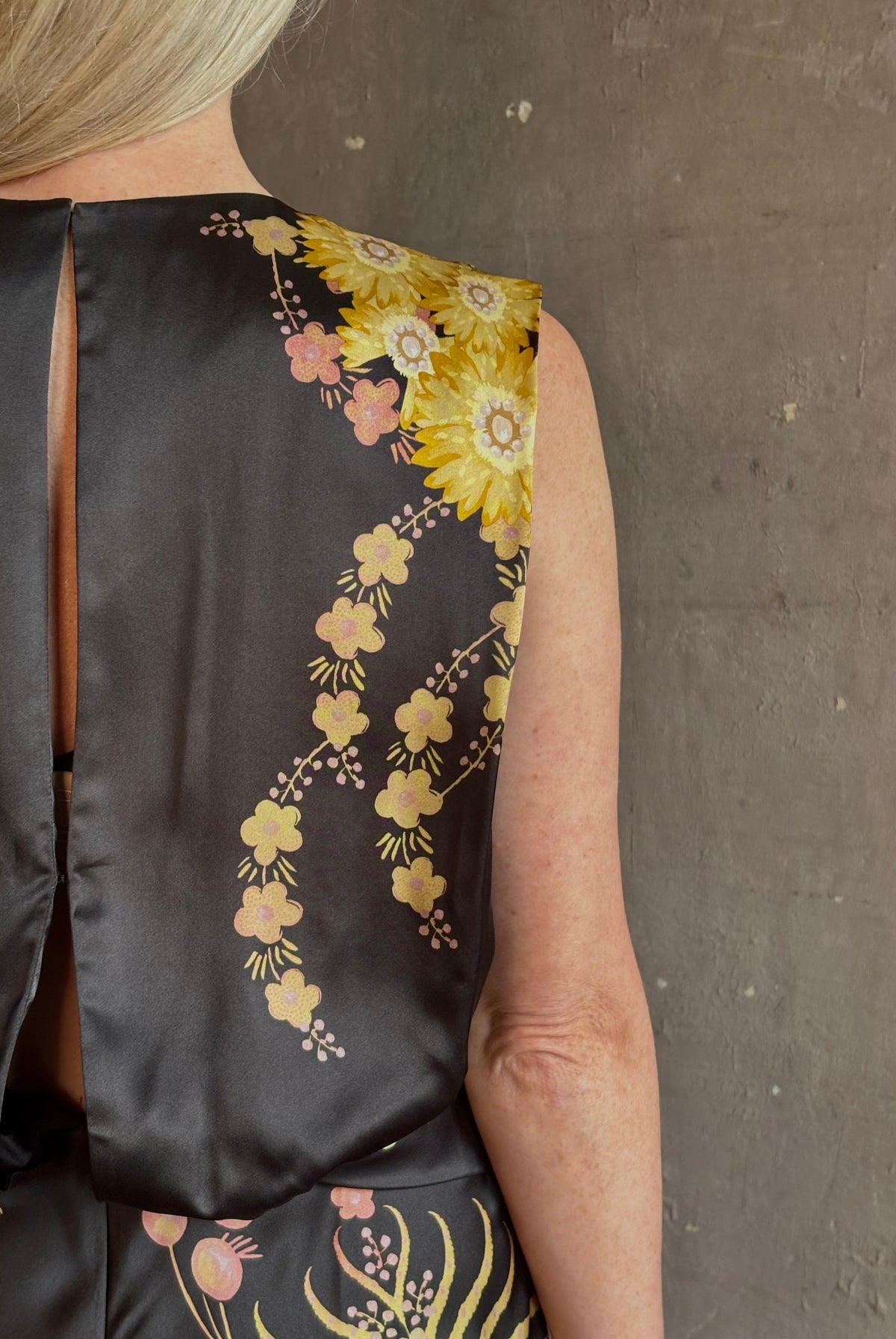 Mature woman wearing Saloni Gwen Dress in Golden Palm semi-open back gathered waist black with yellow and pink print evening gown