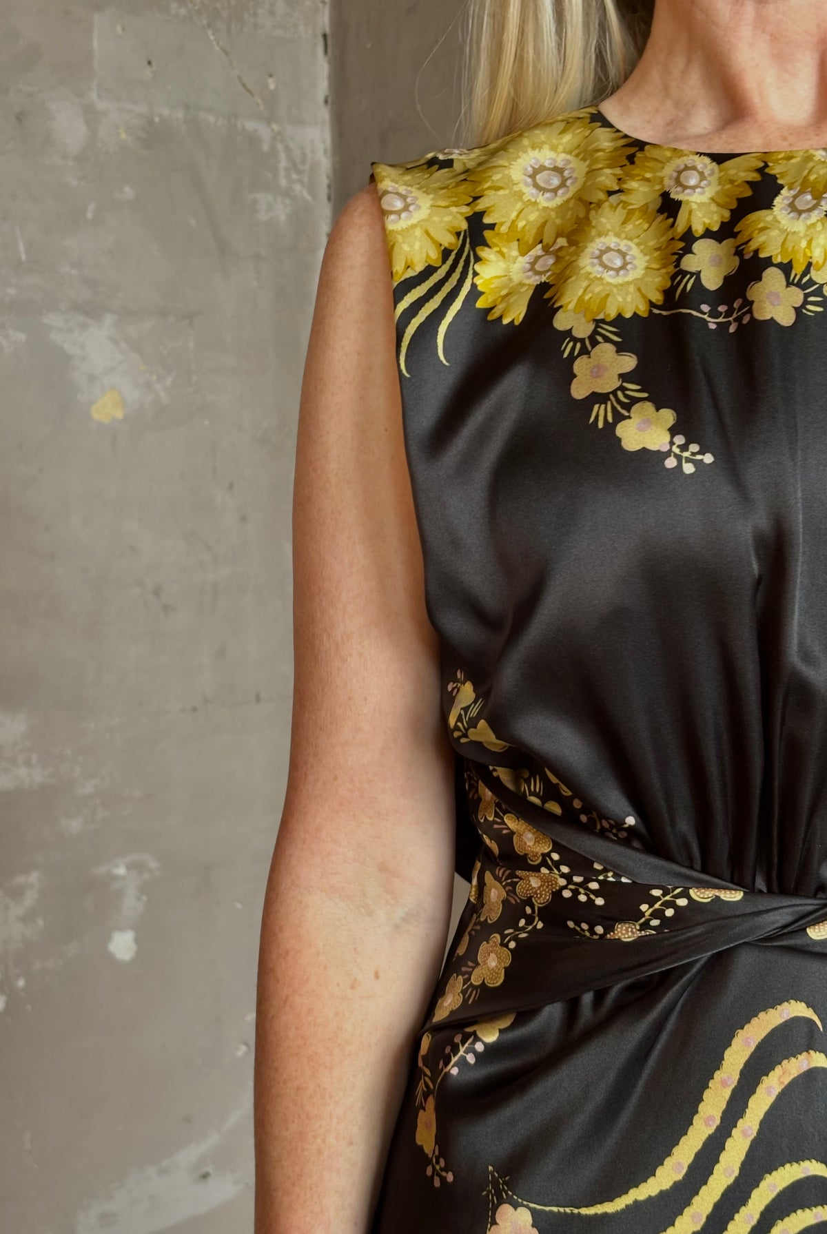 Mature woman wearing Saloni Gwen Dress in Golden Palm semi-open back gathered waist black with yellow and pink print evening gown